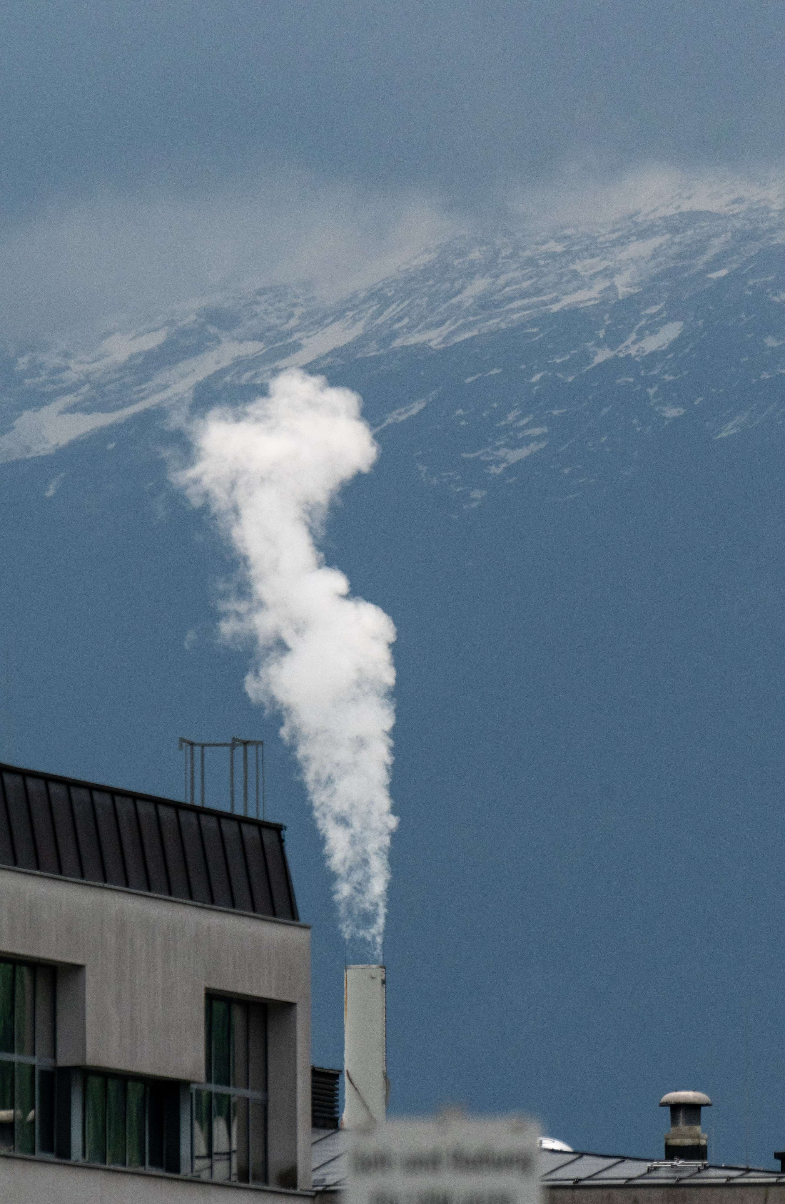 There is a smoke coming out of a chimney on a building.