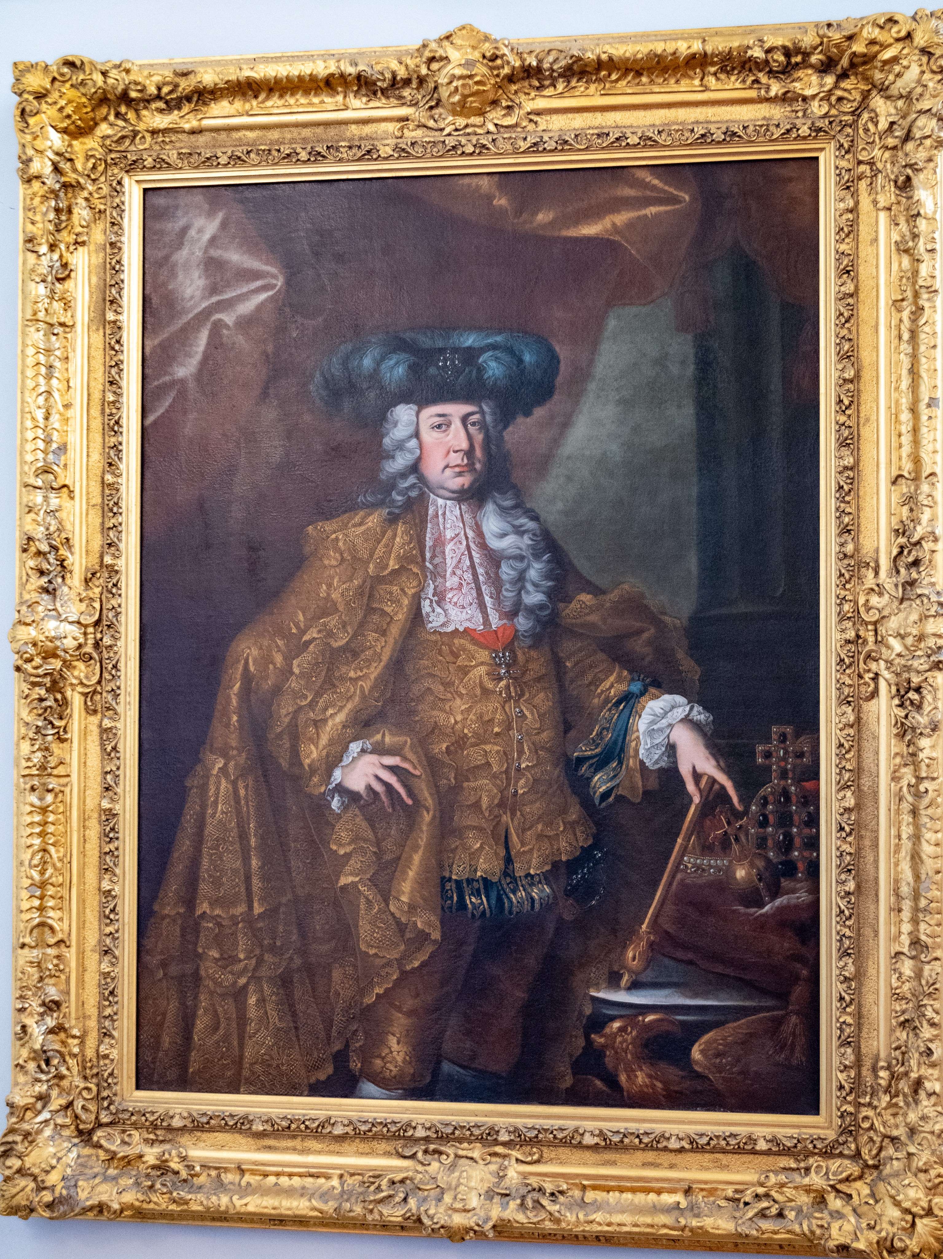 Painting of a man in a golden coat and hat holding a cane.