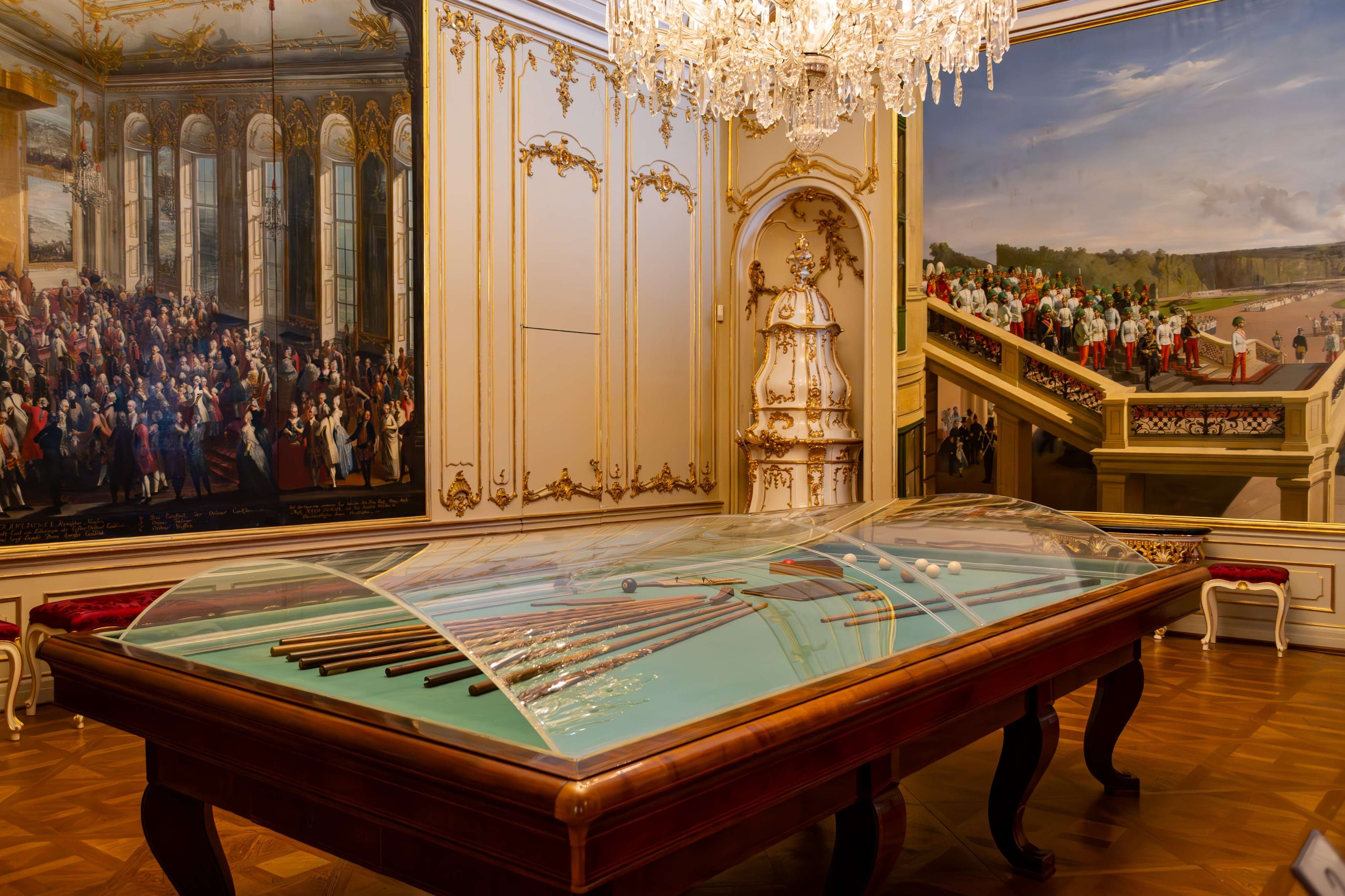 There is a table with a glass top in a room with paintings.
