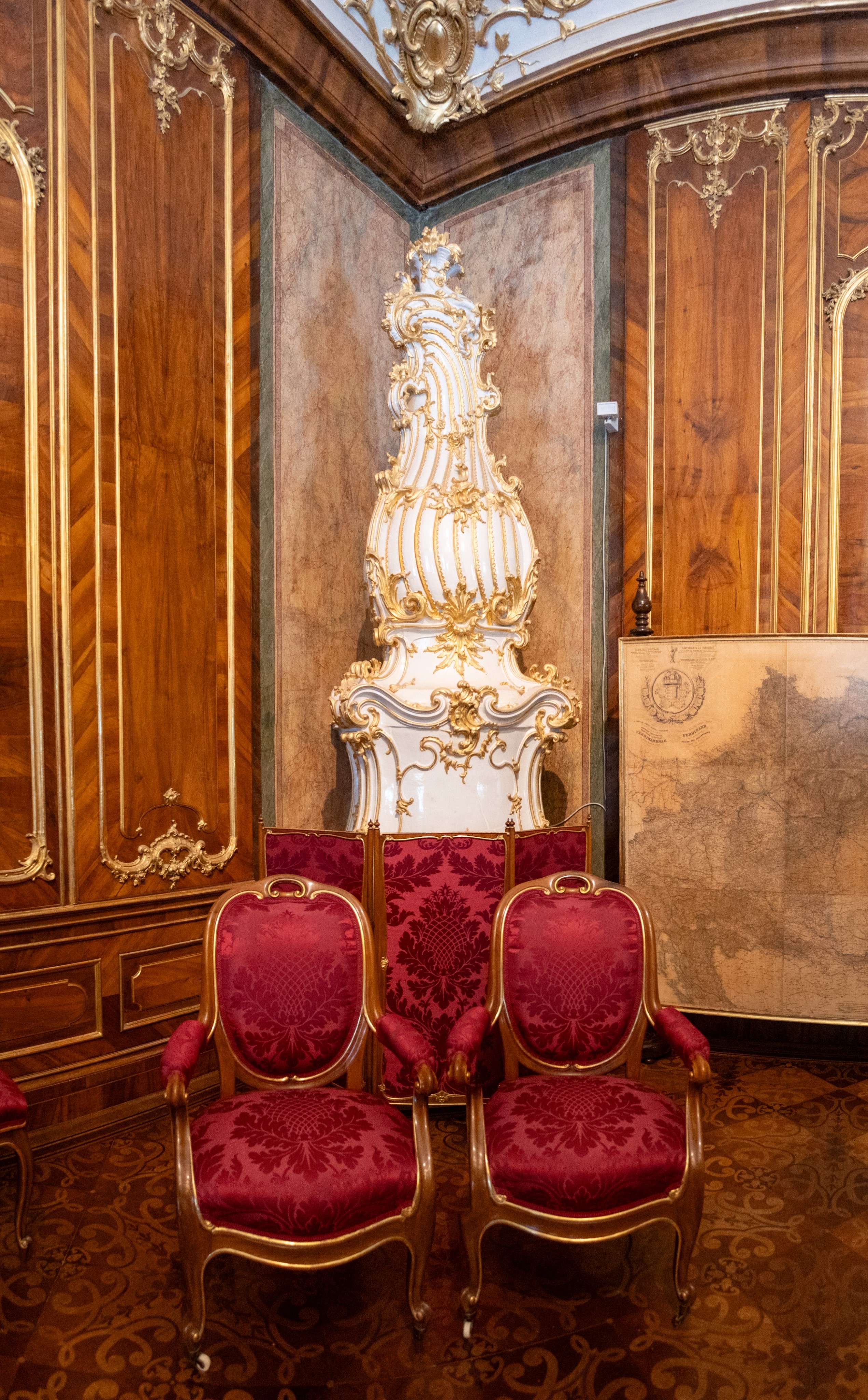 There are four chairs in a room with a large clock on the wall.