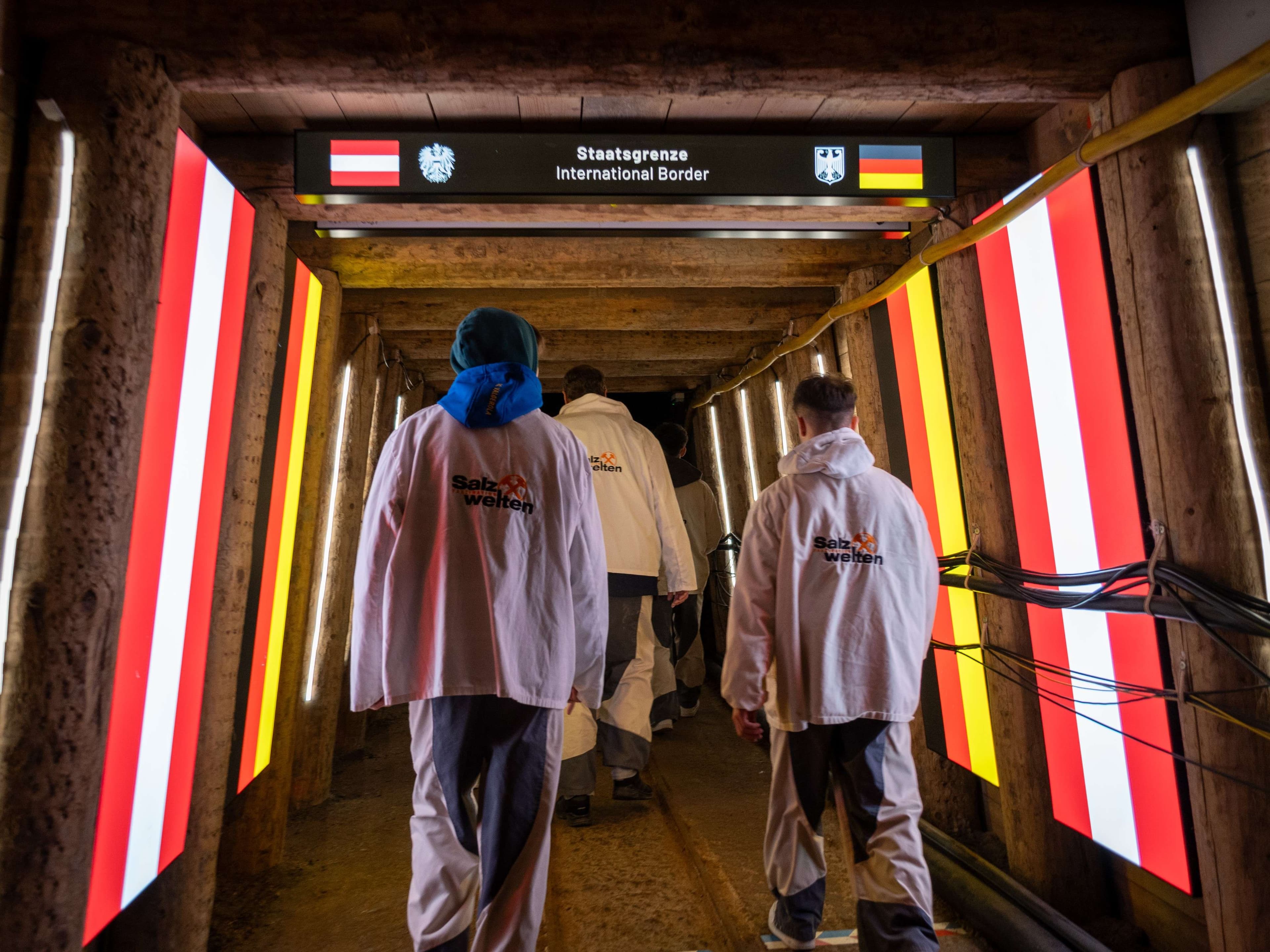 People walking in a tunnel with neon lights and signs.