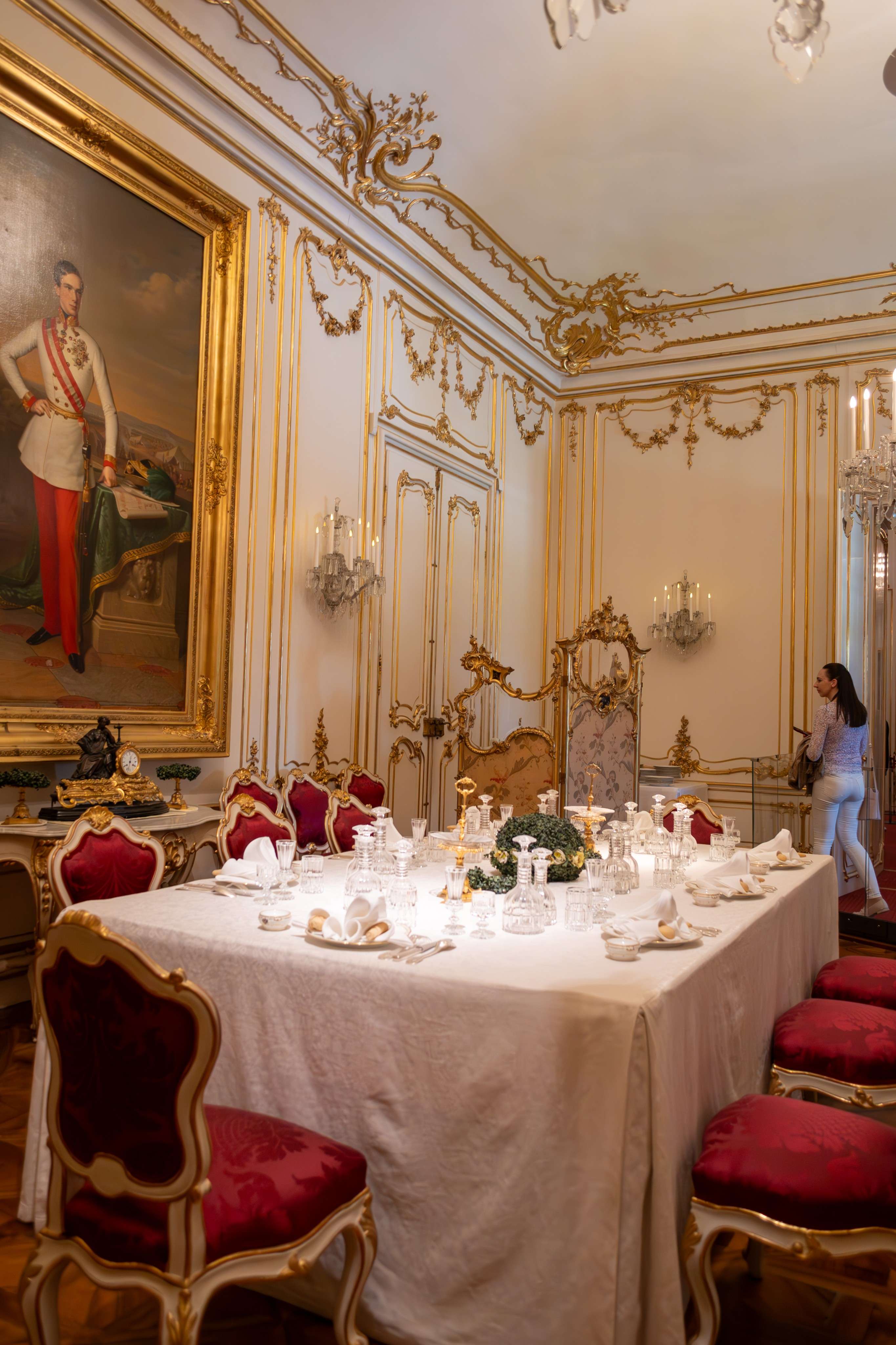 There is a table with a white table cloth and red chairs.