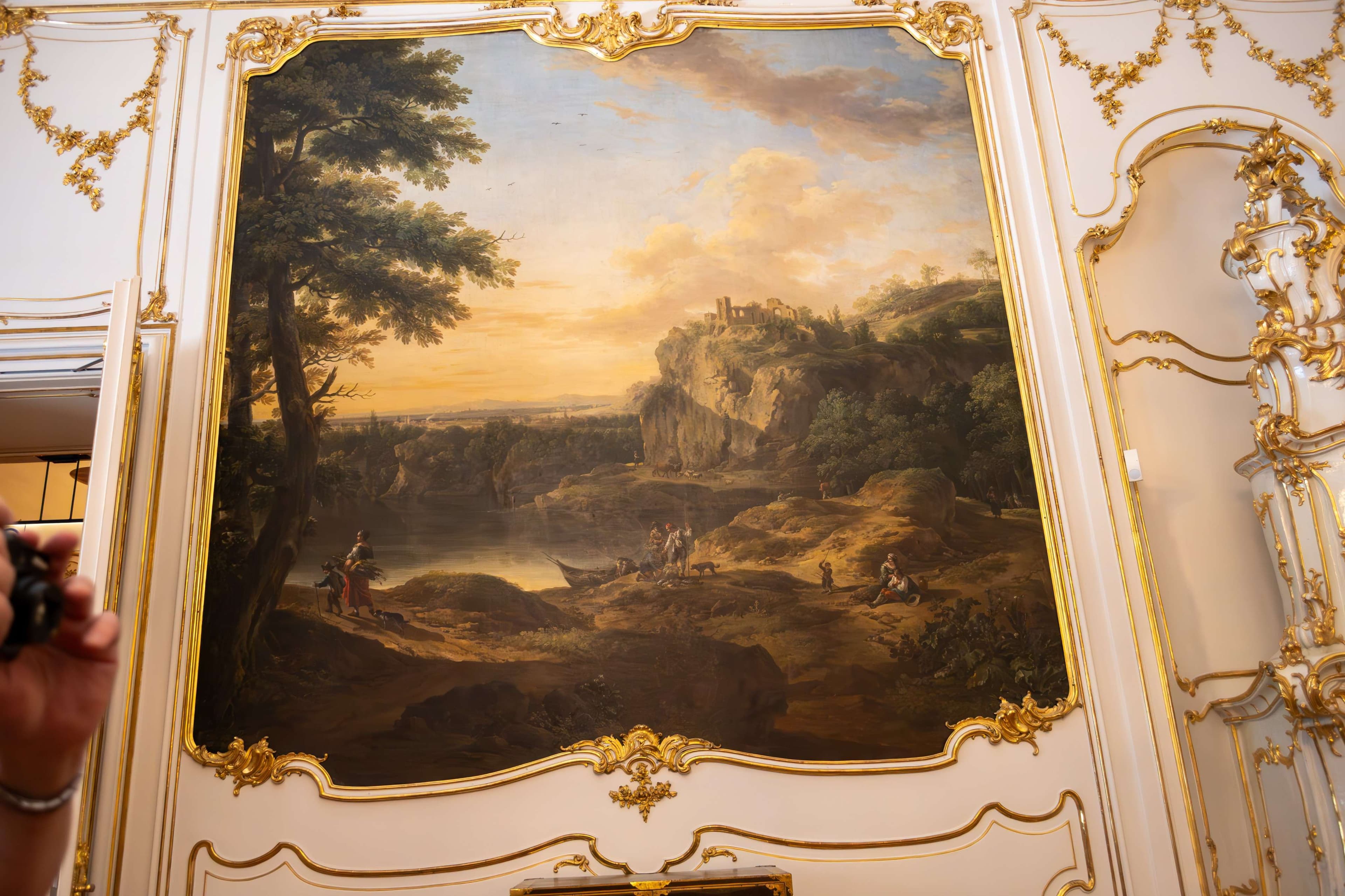 Painting of a landscape with figures in a mountainous landscape with a man taking a picture.