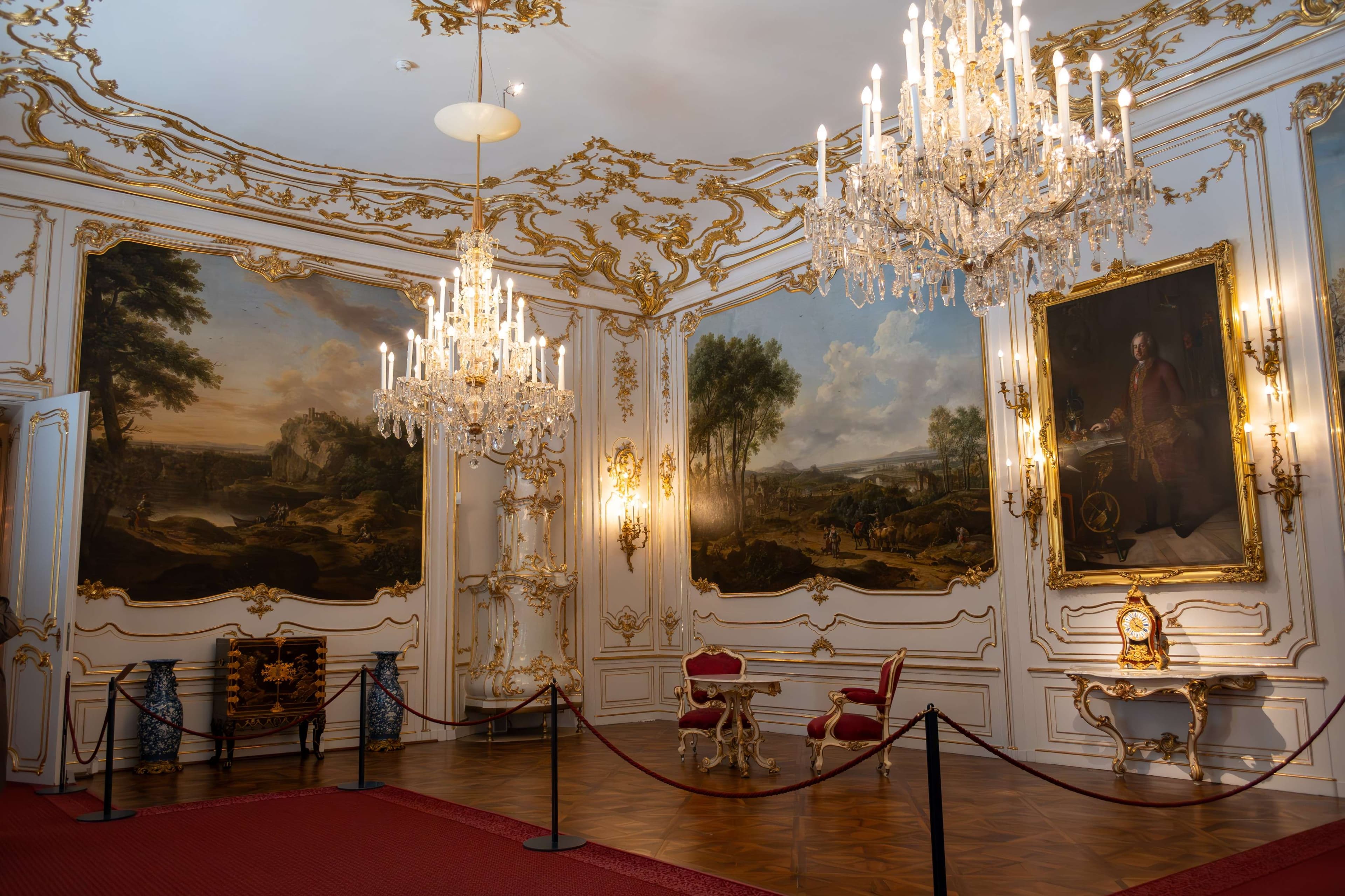 There is a room with a chandelier and a painting on the wall.