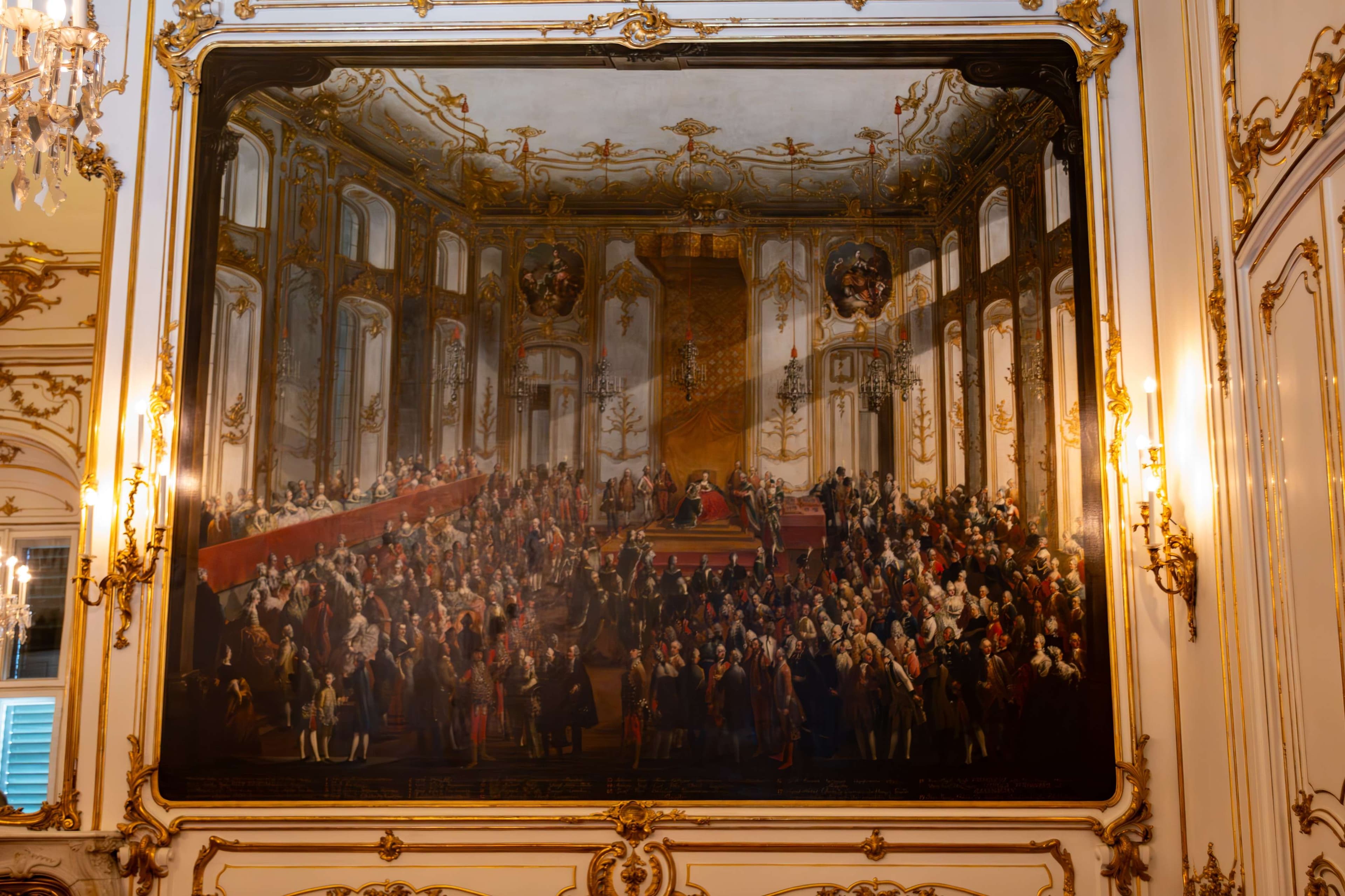 Painting of a large group of people in a room with a chandelier.