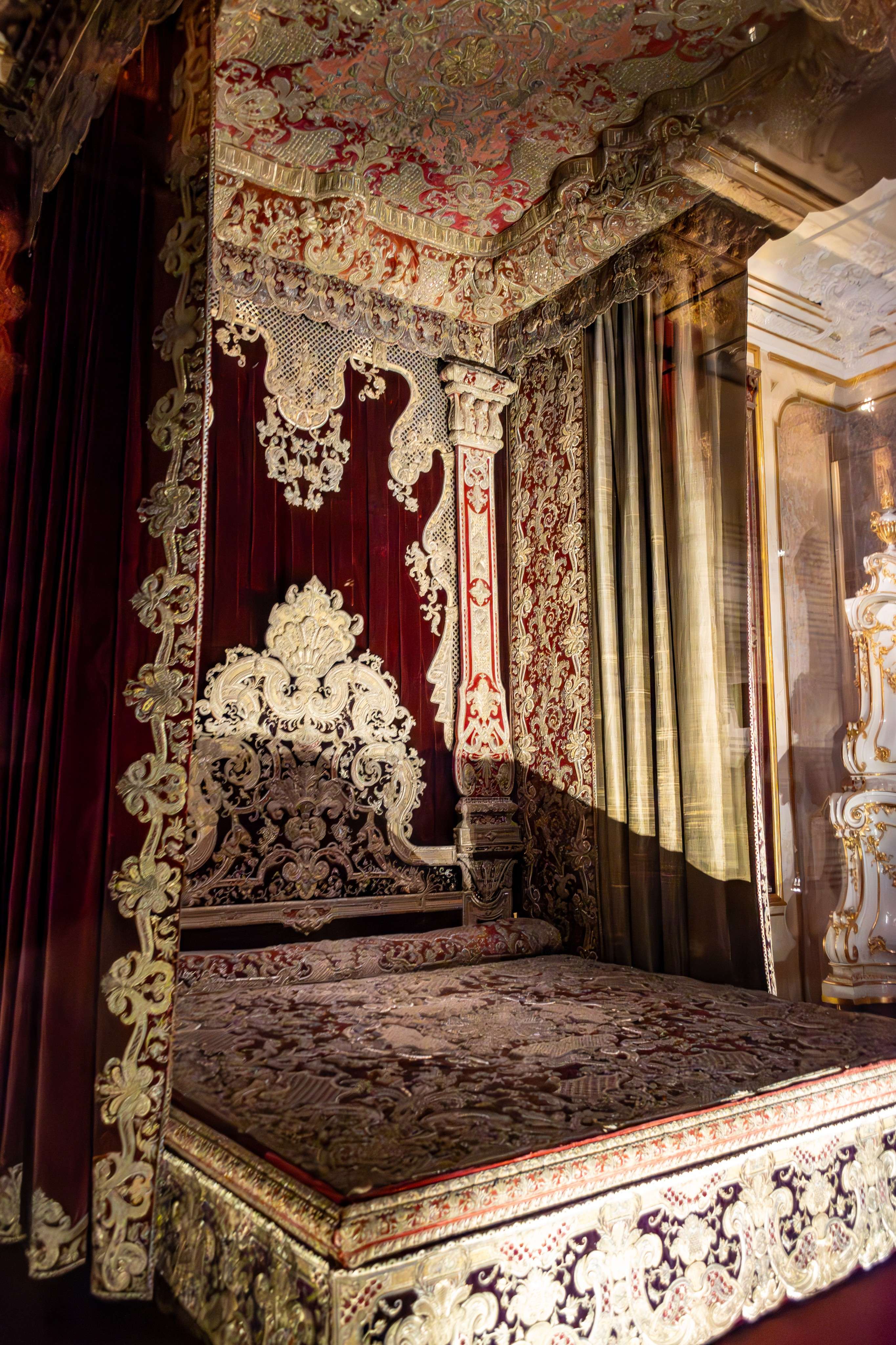 Arafed bed with a red and gold bed cover and a red and gold canopy.