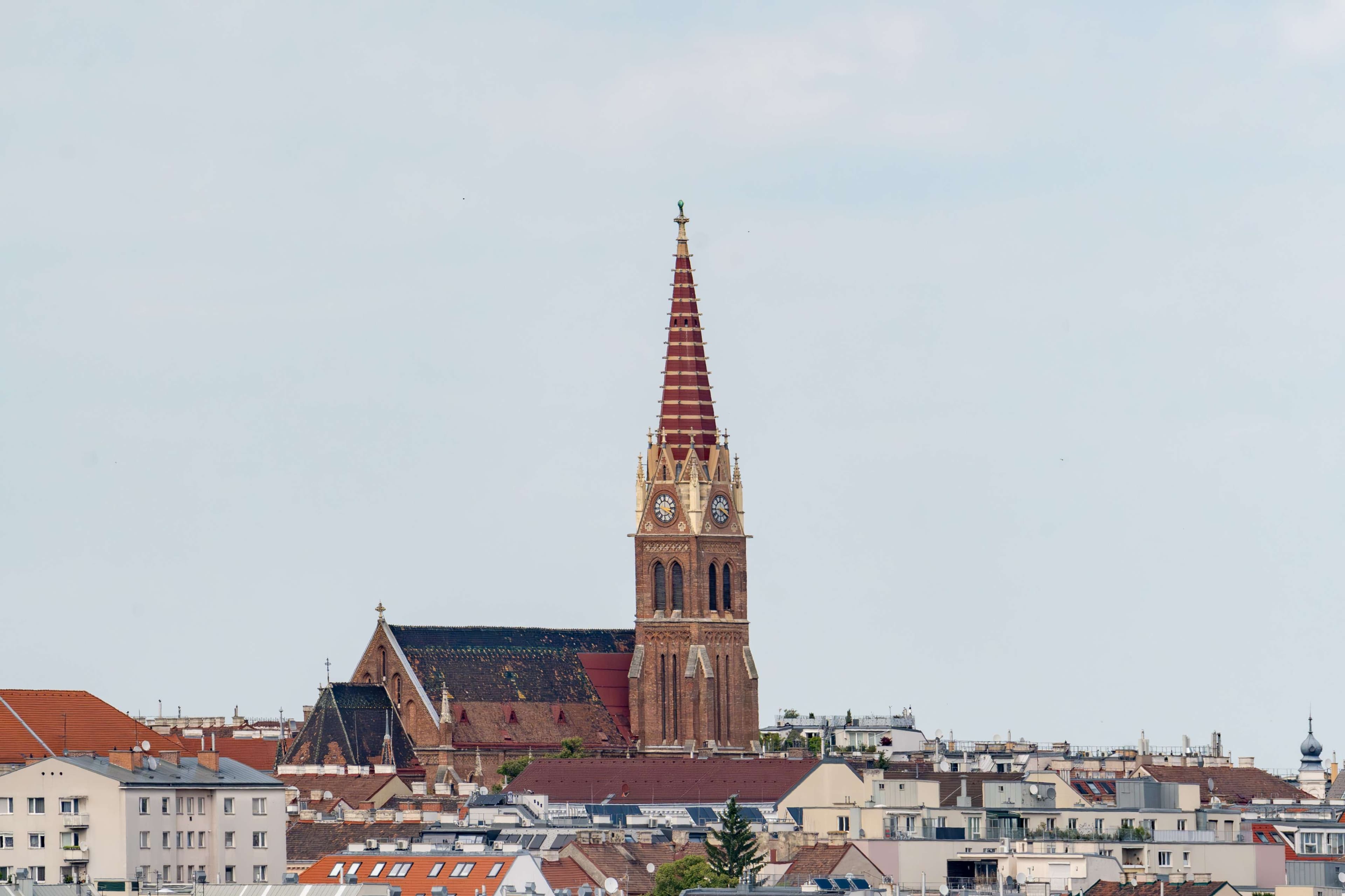 There is a large tower with a clock on it in the middle of a city.