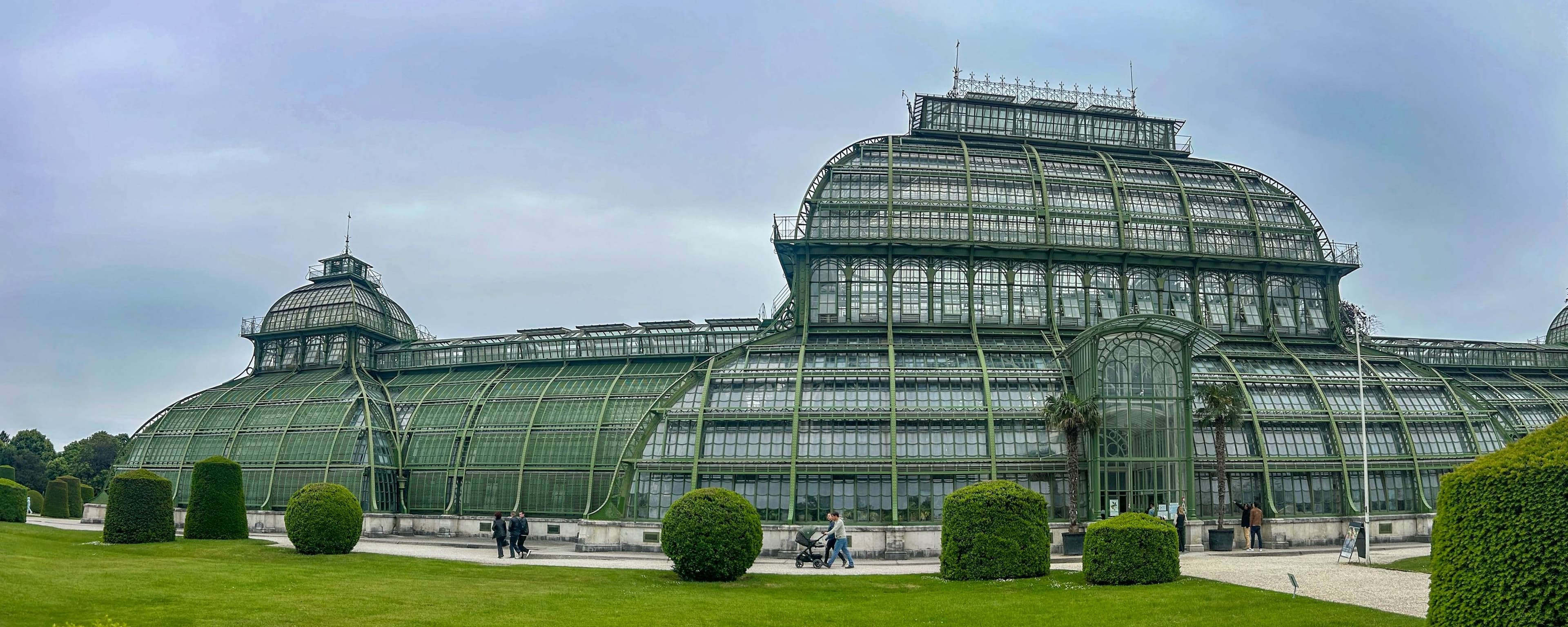 Araffes in front of a large glass building with a clock on top.