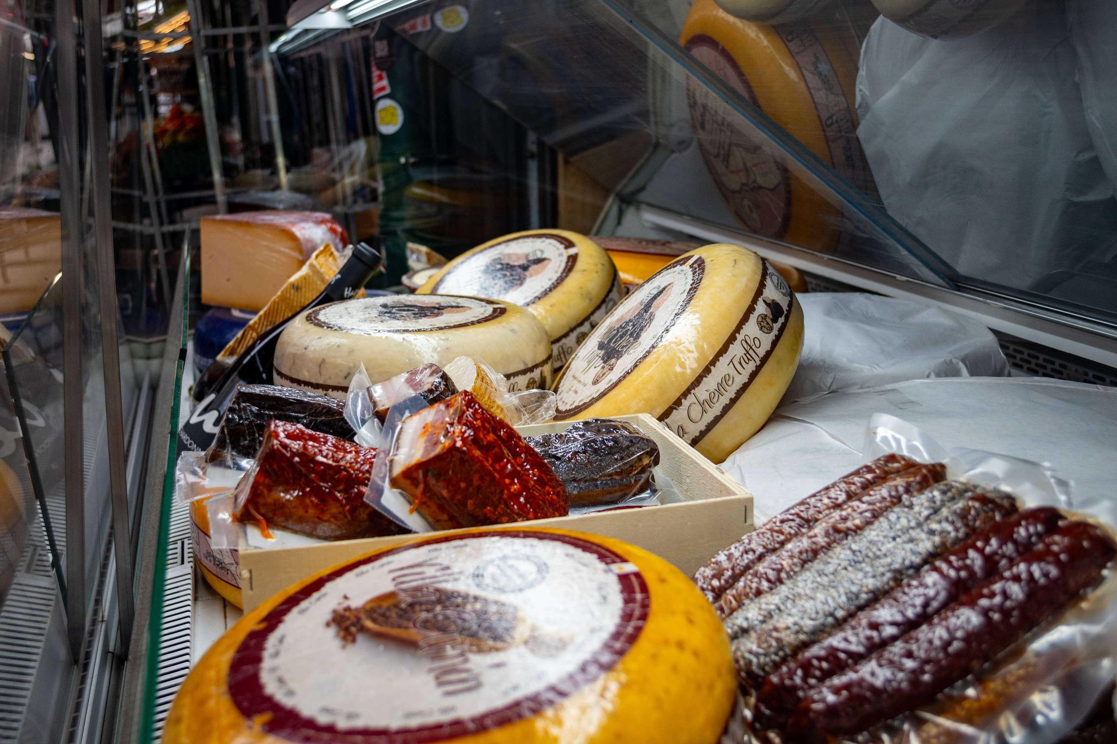 There are many different types of cheeses on display in a store.