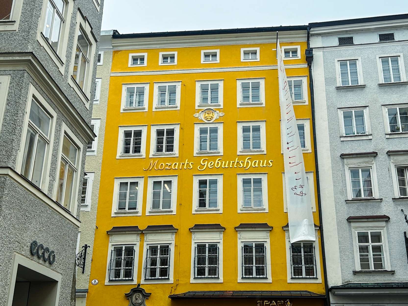 Yellow building with a clock on the front of it in a city.
