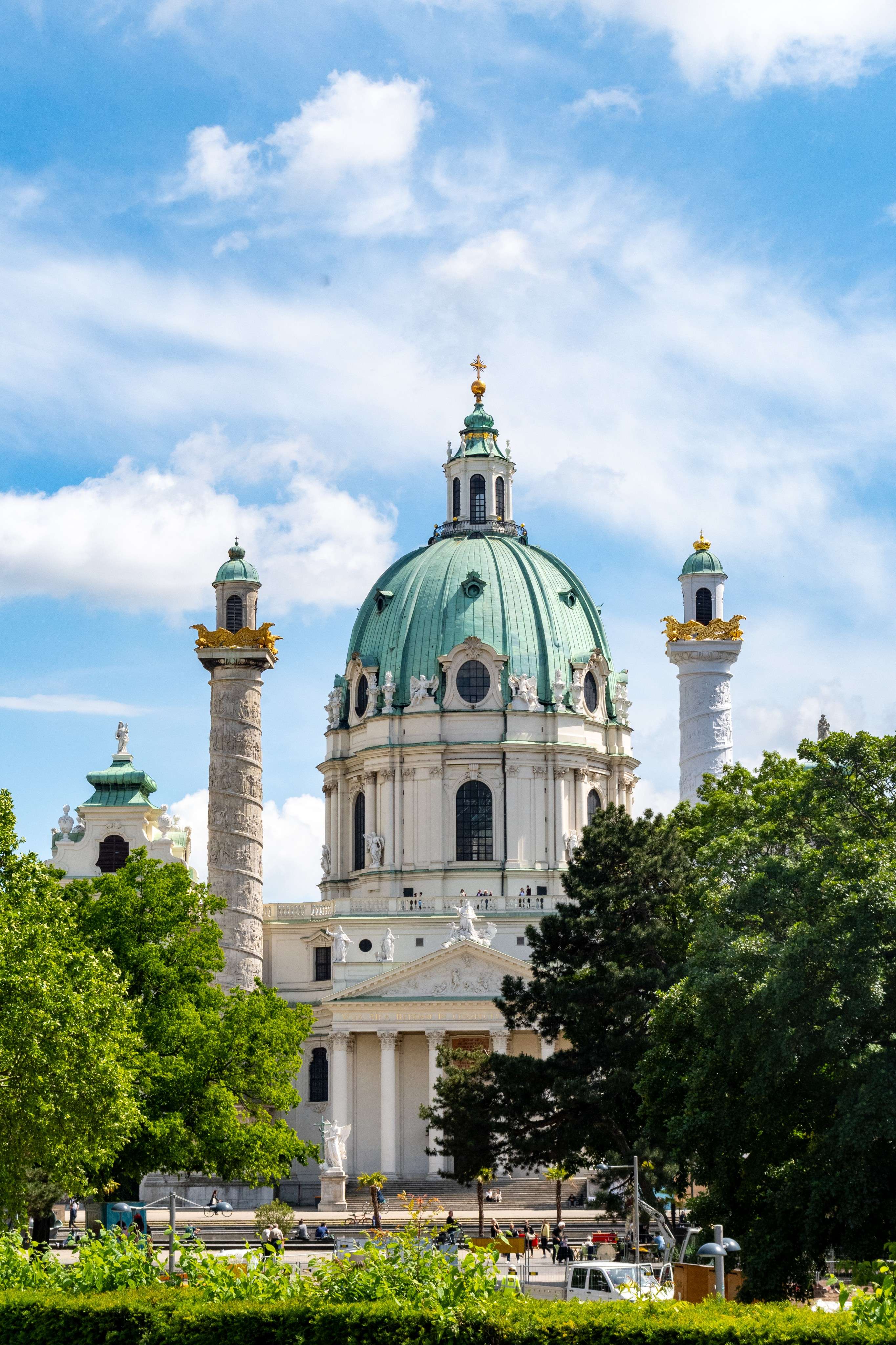There is a large white building with a green dome and a clock tower.