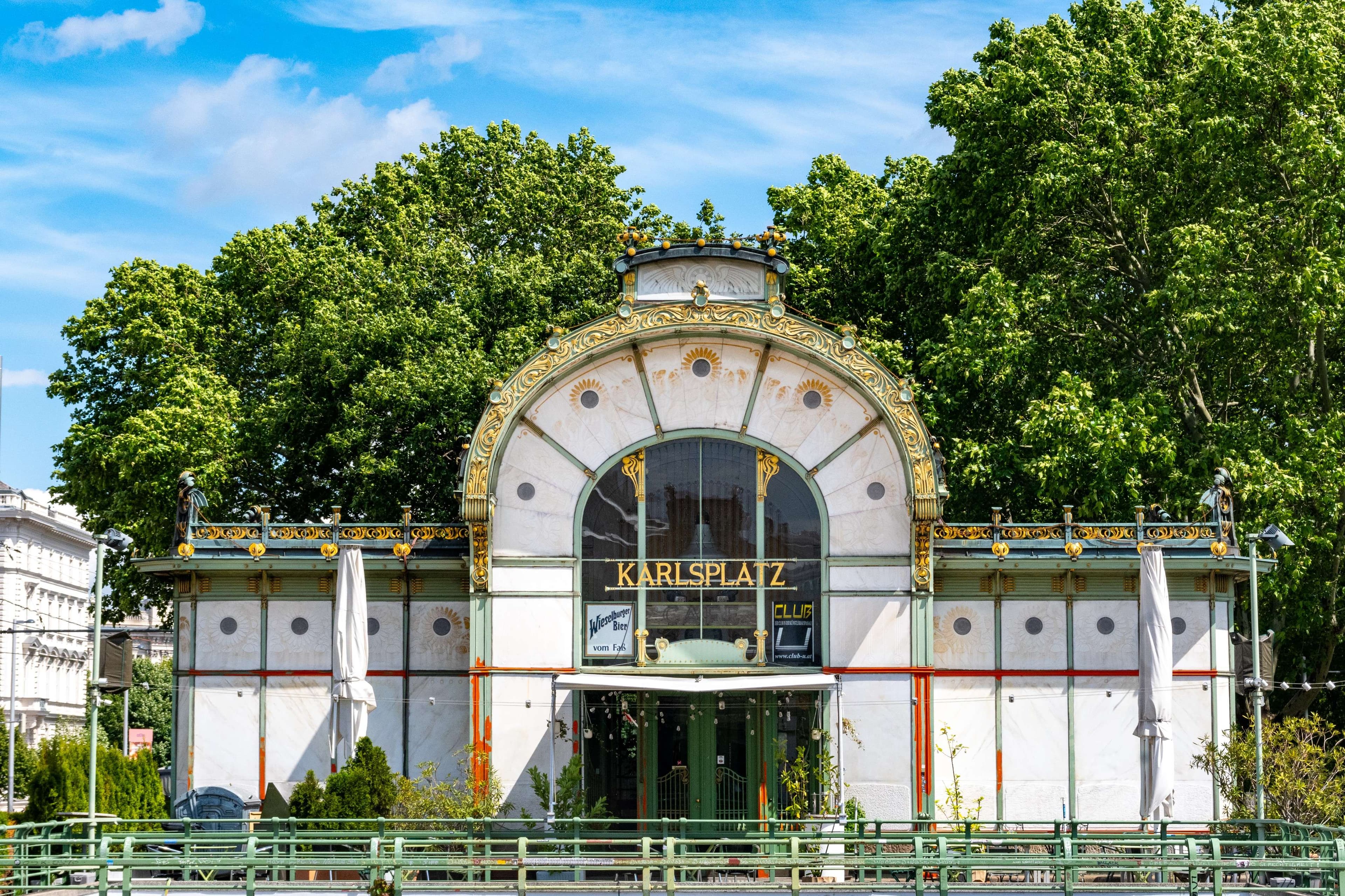There is a building with a large arched window and a green fence.