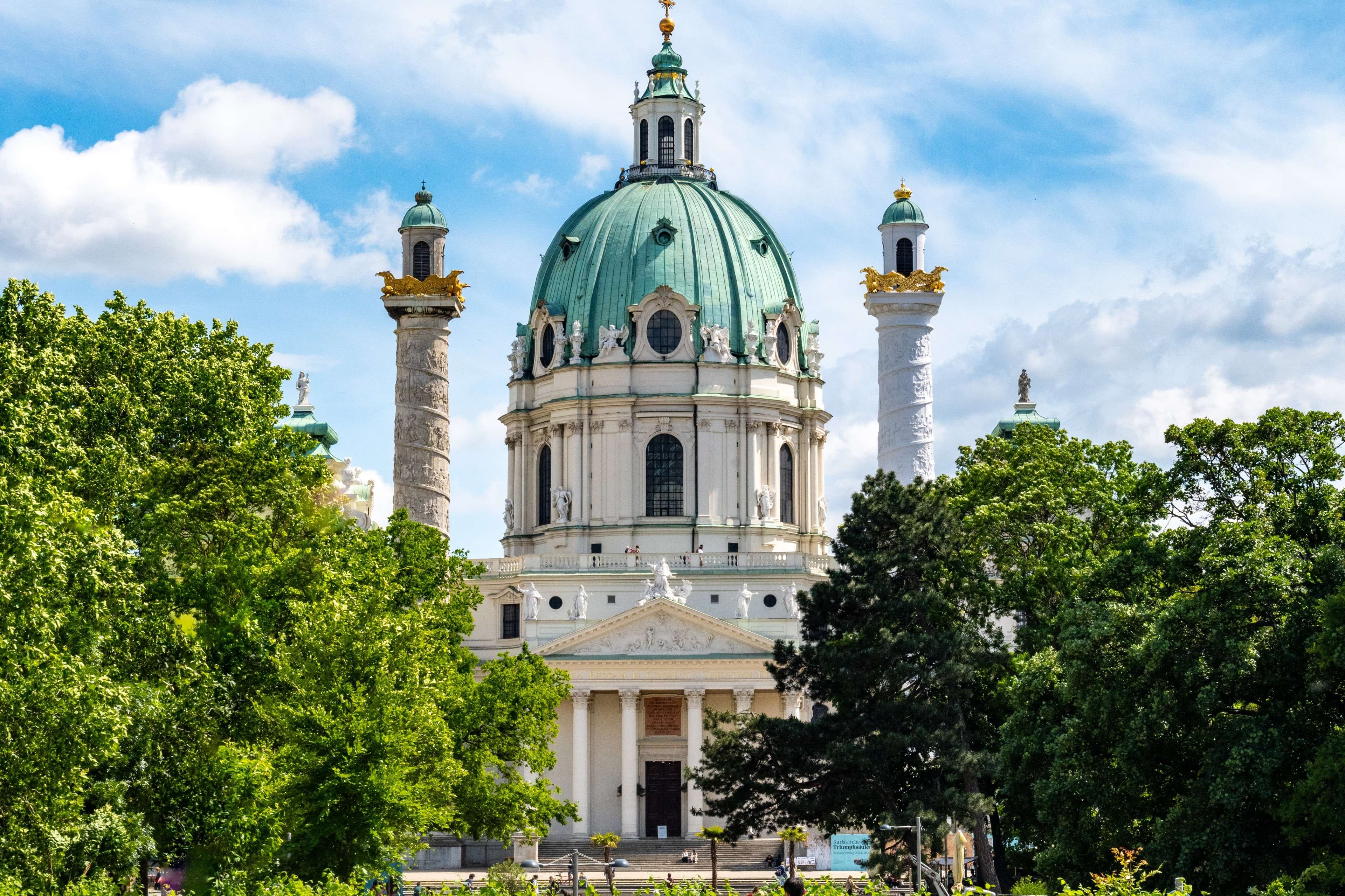 There is a large building with a green dome and a clock tower.