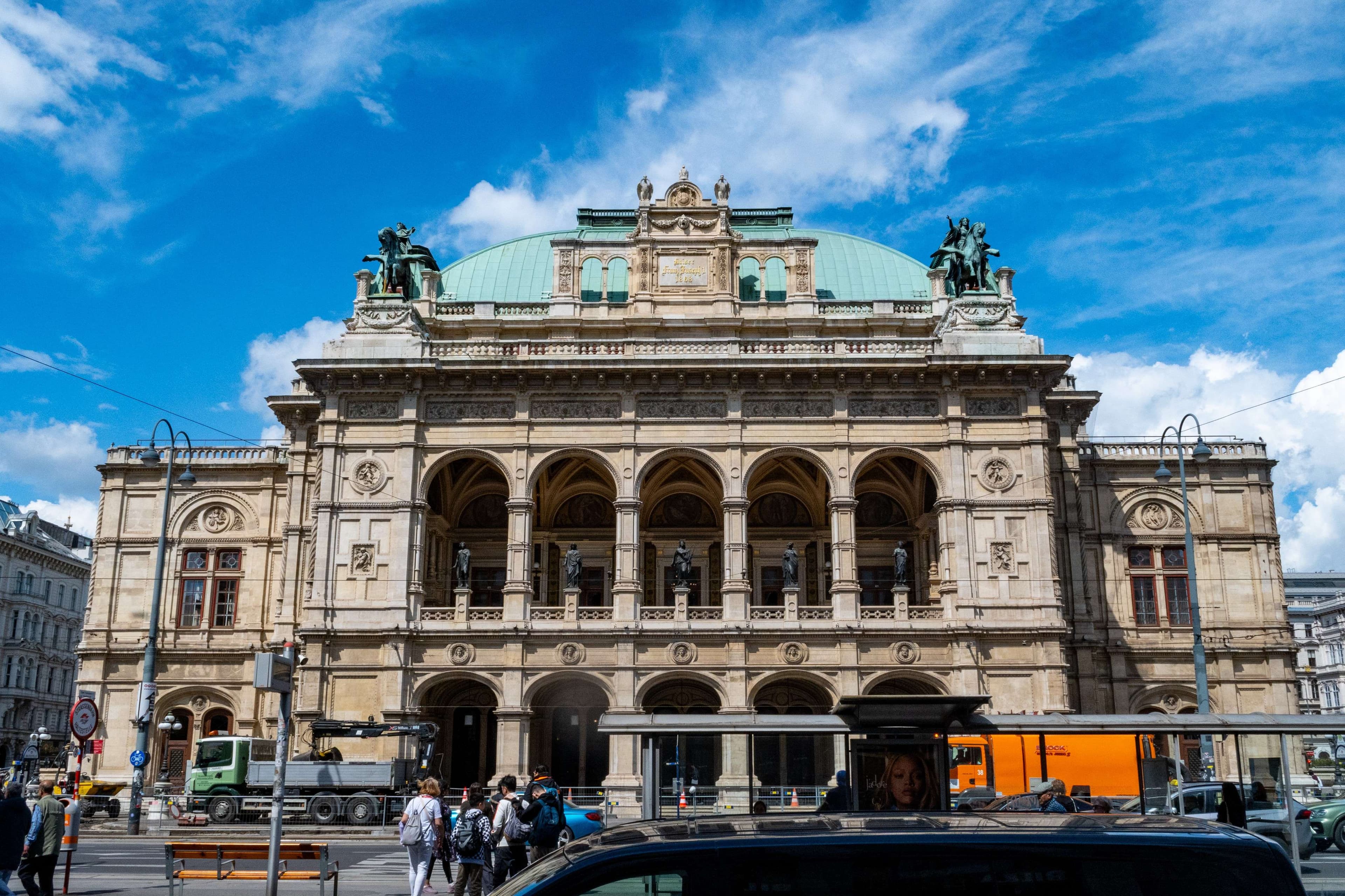 There is a large building with a green roof and a car parked in front of it.