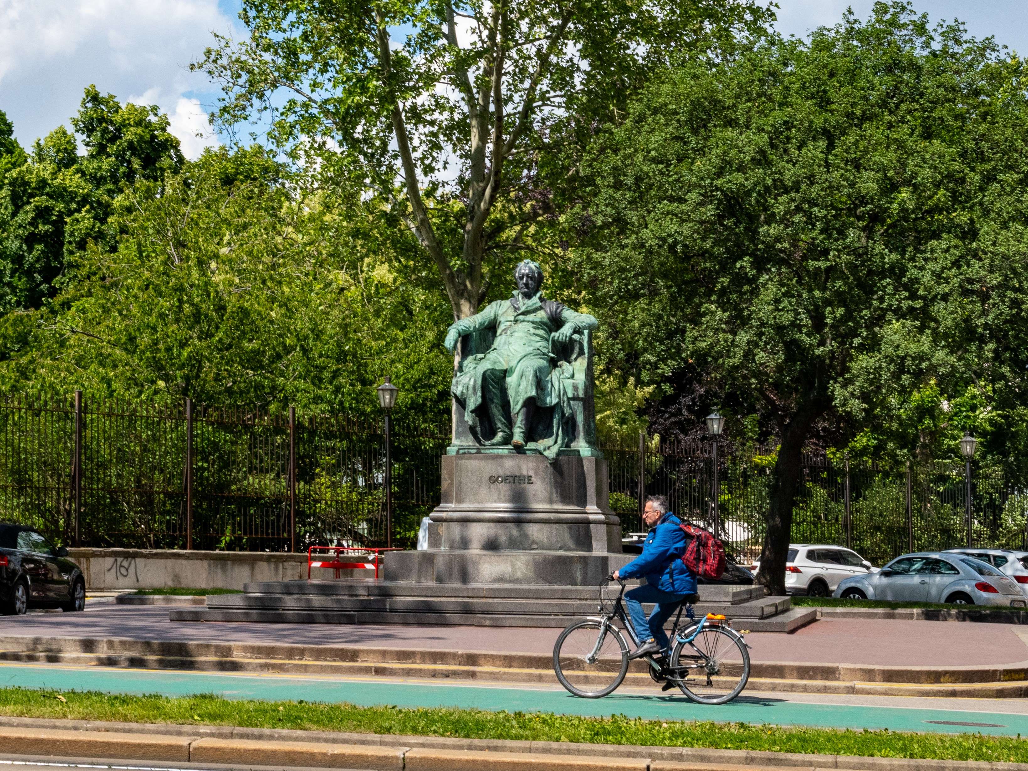 There is a man riding a bike in the street with a backpack.