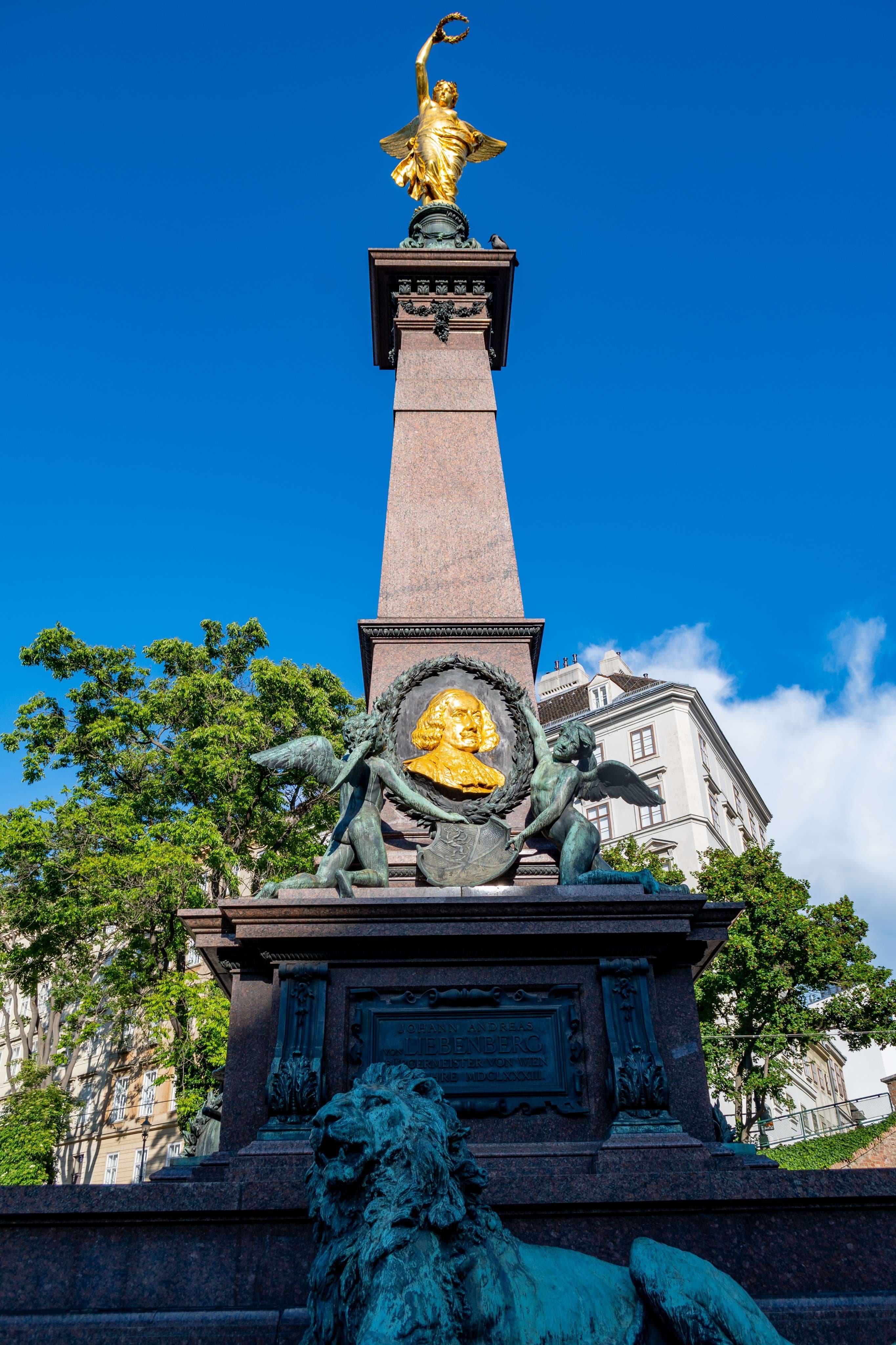 There is a statue of a lion with a gold head on top of a monument.