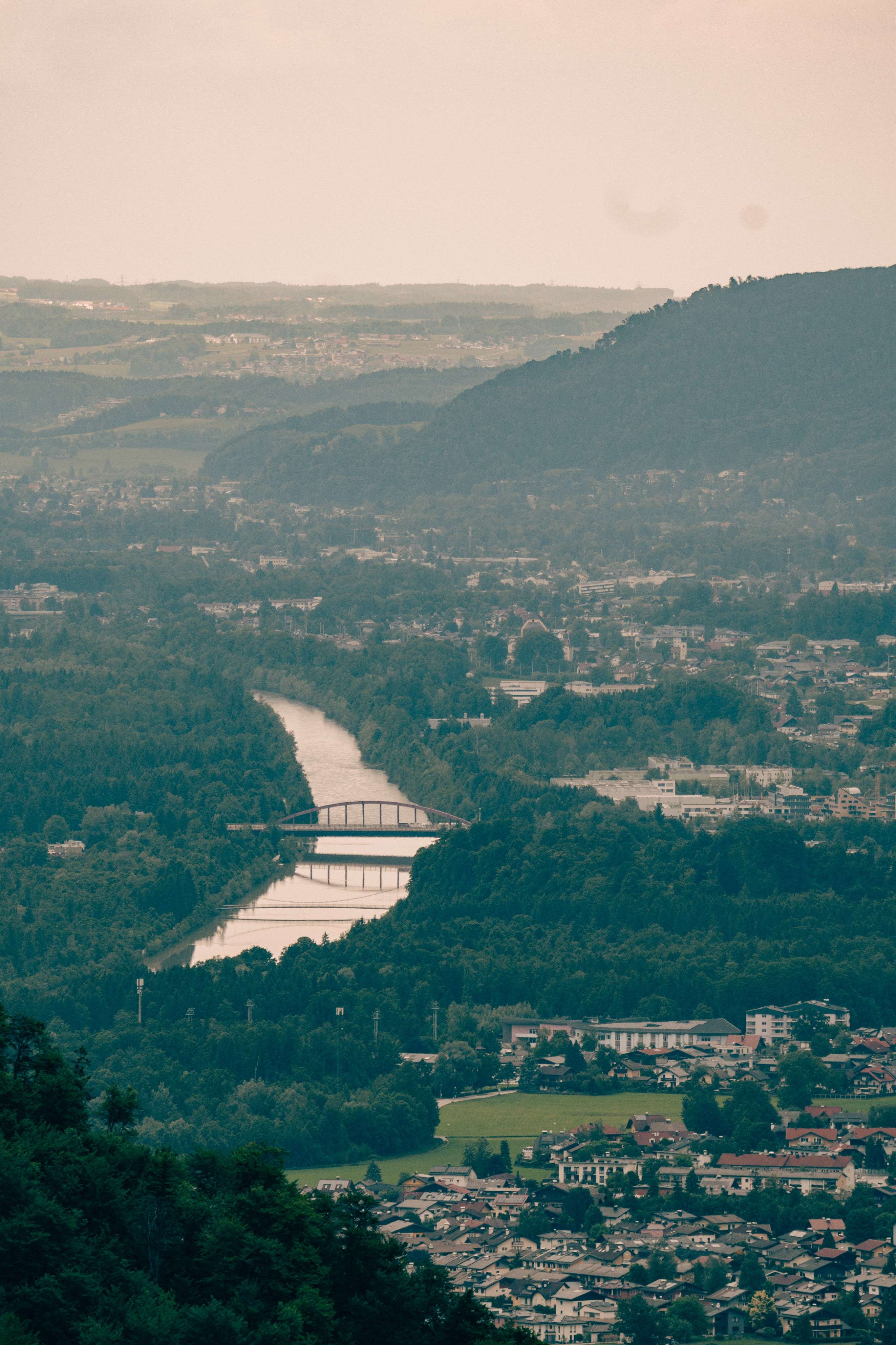 There is a view of a river and a bridge from a hill.