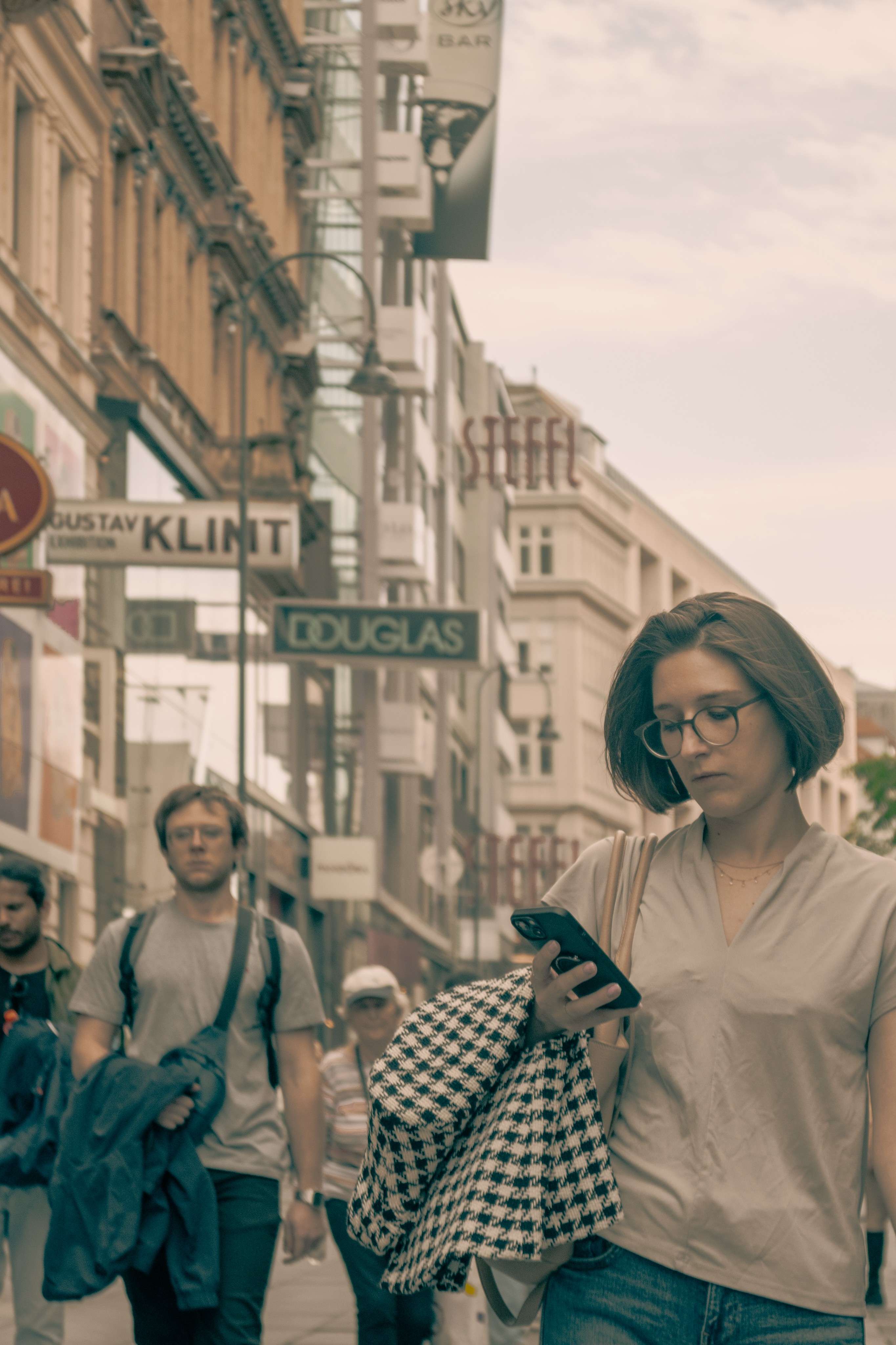 Woman walking down the street with a cell phone in her hand.