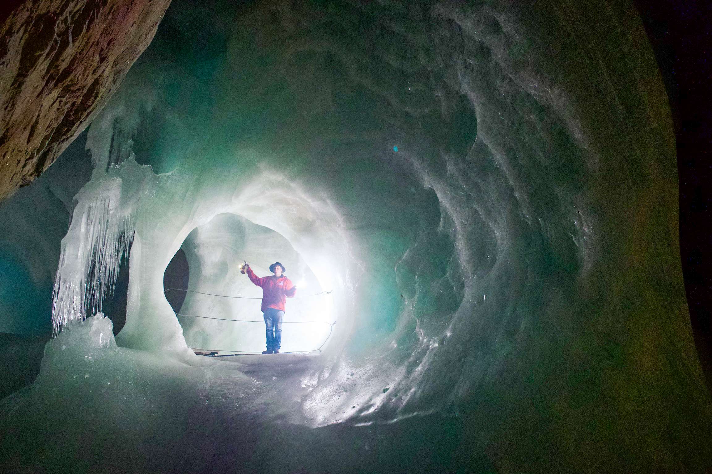 There is a man standing in a cave with a light shining through it.