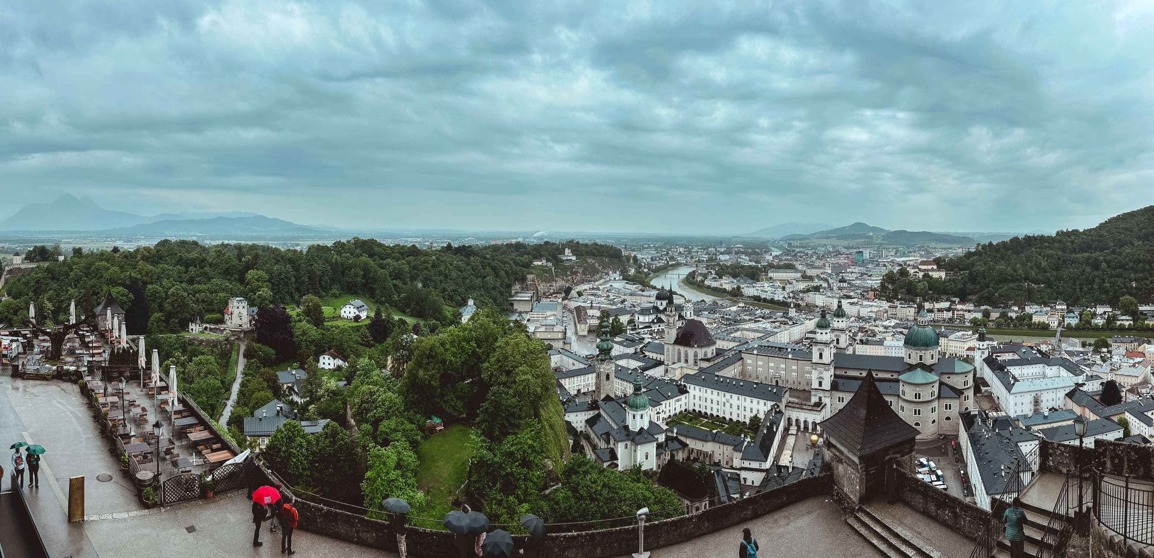 There are people walking on a walkway with umbrellas in the rain.