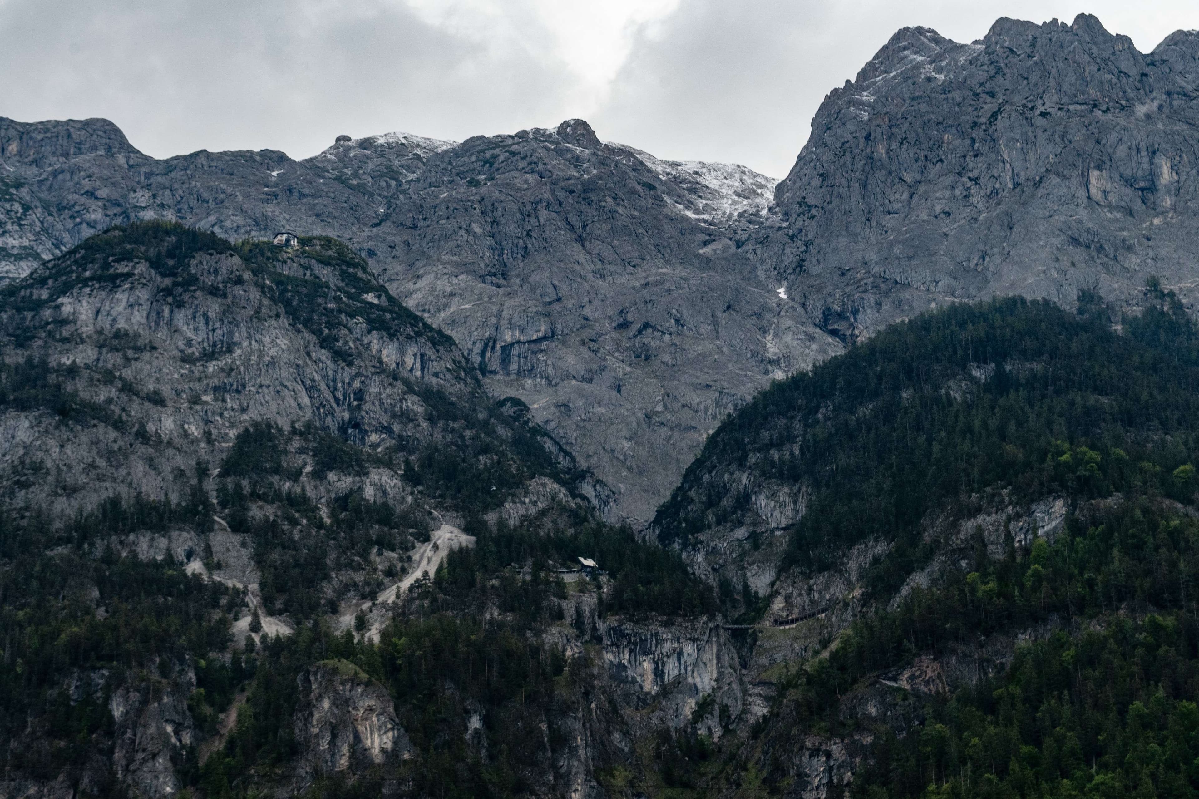 Mountains with a few trees and a bird flying in the sky.