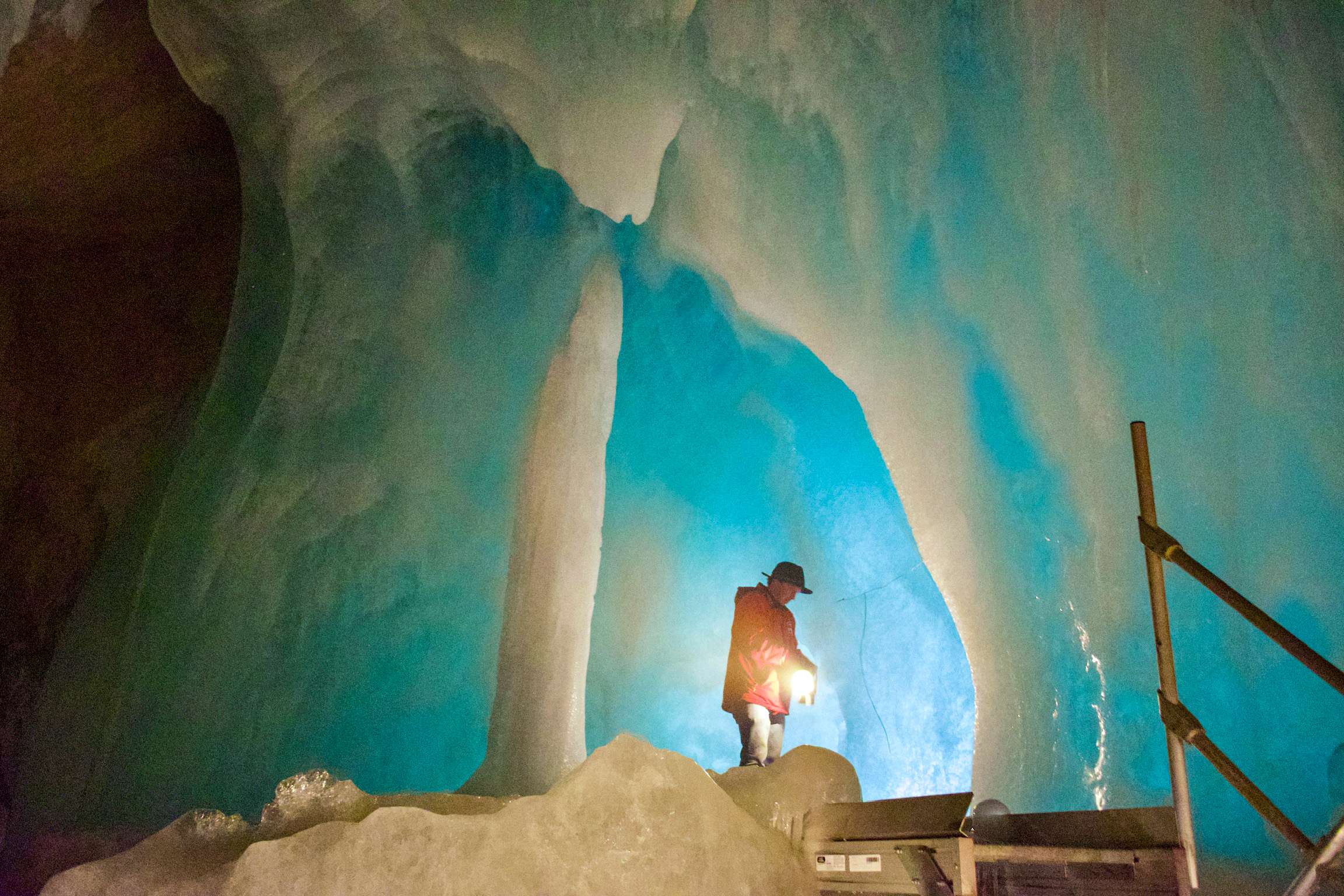 There is a man standing in a cave with a lantern.