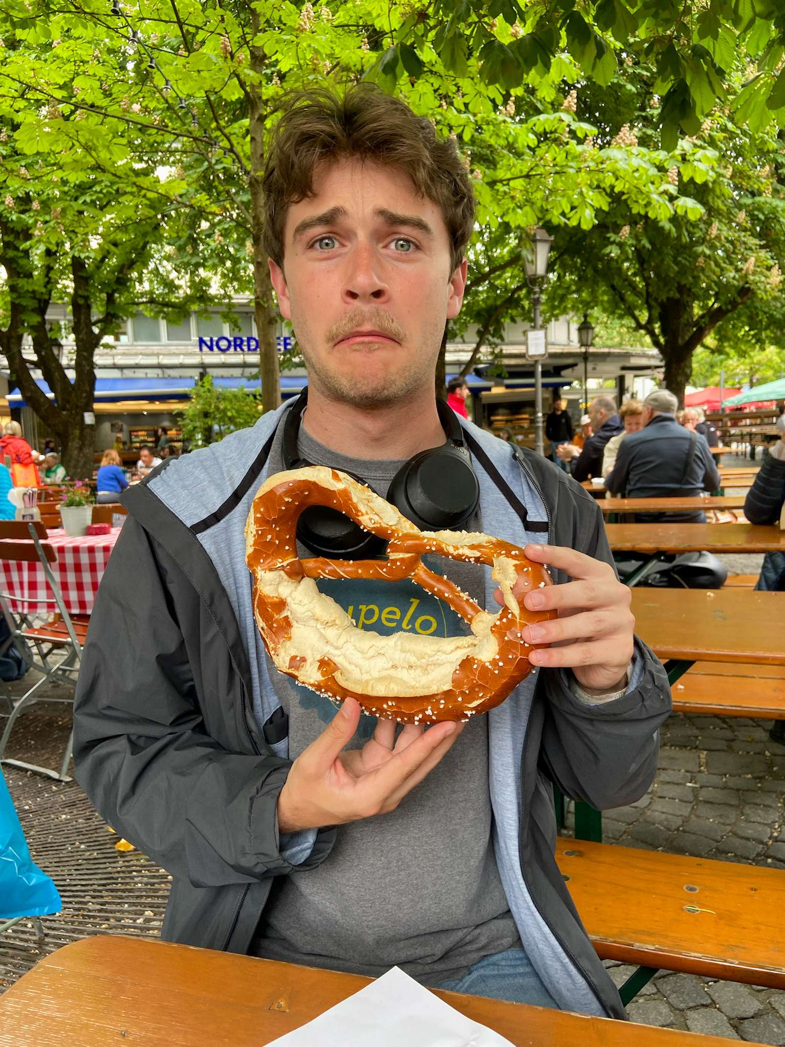 Araffe with a large pretzel in his hands at a table.