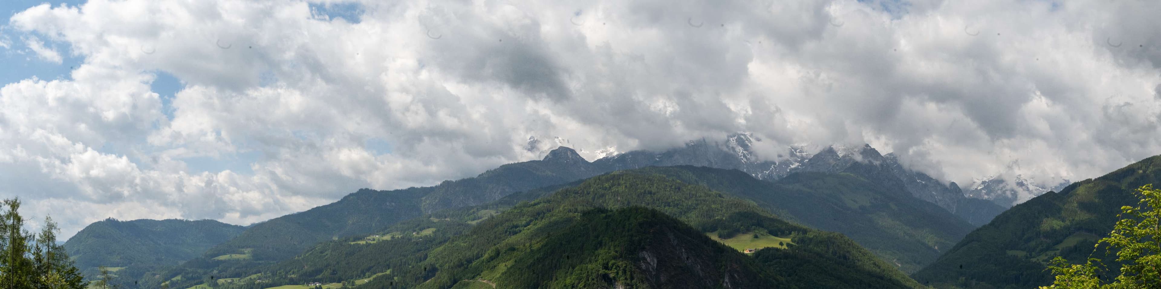 Mountains with a few clouds in the sky and a cow grazing.