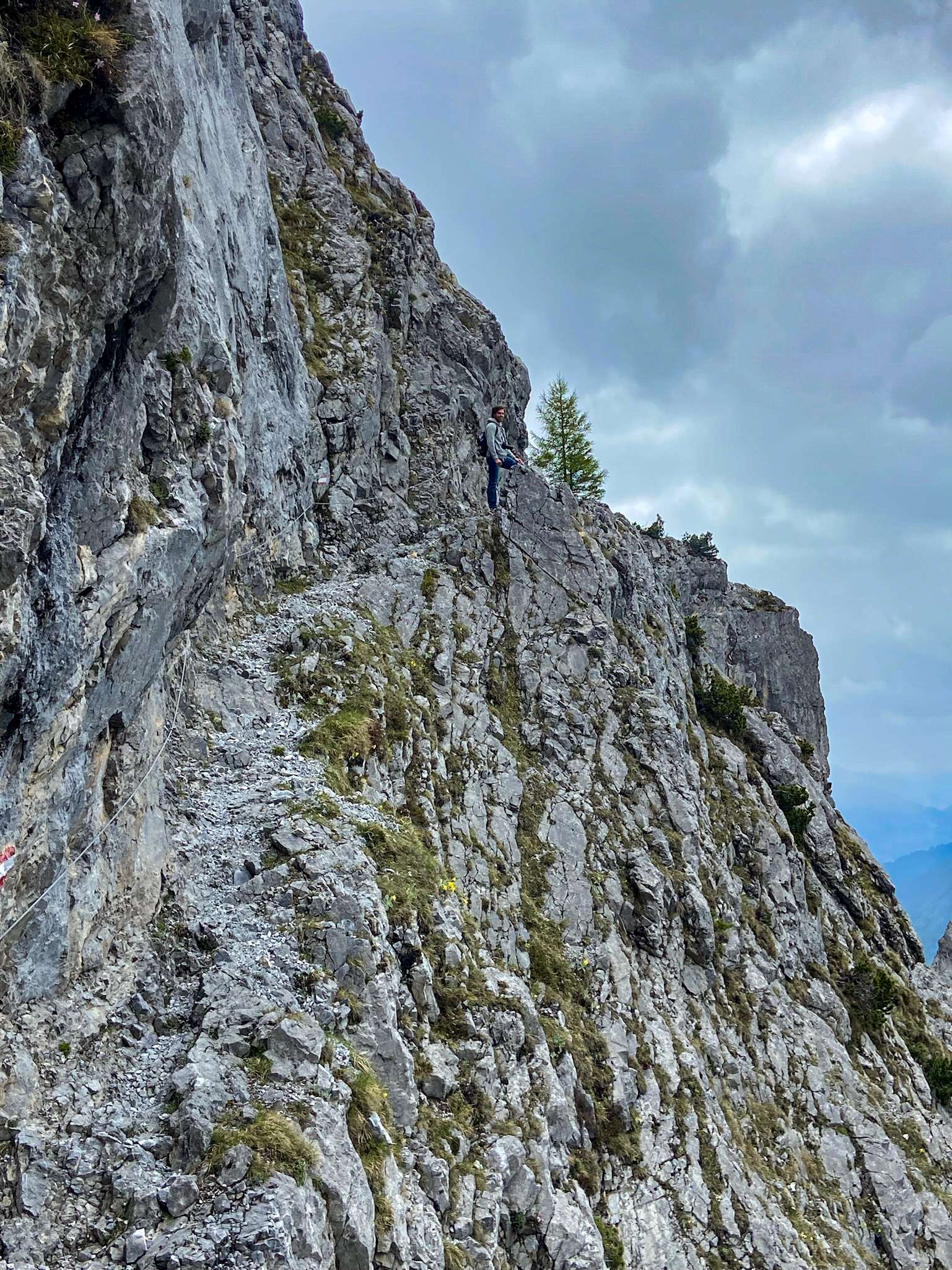 There is a man that is climbing up a mountain on a rock.