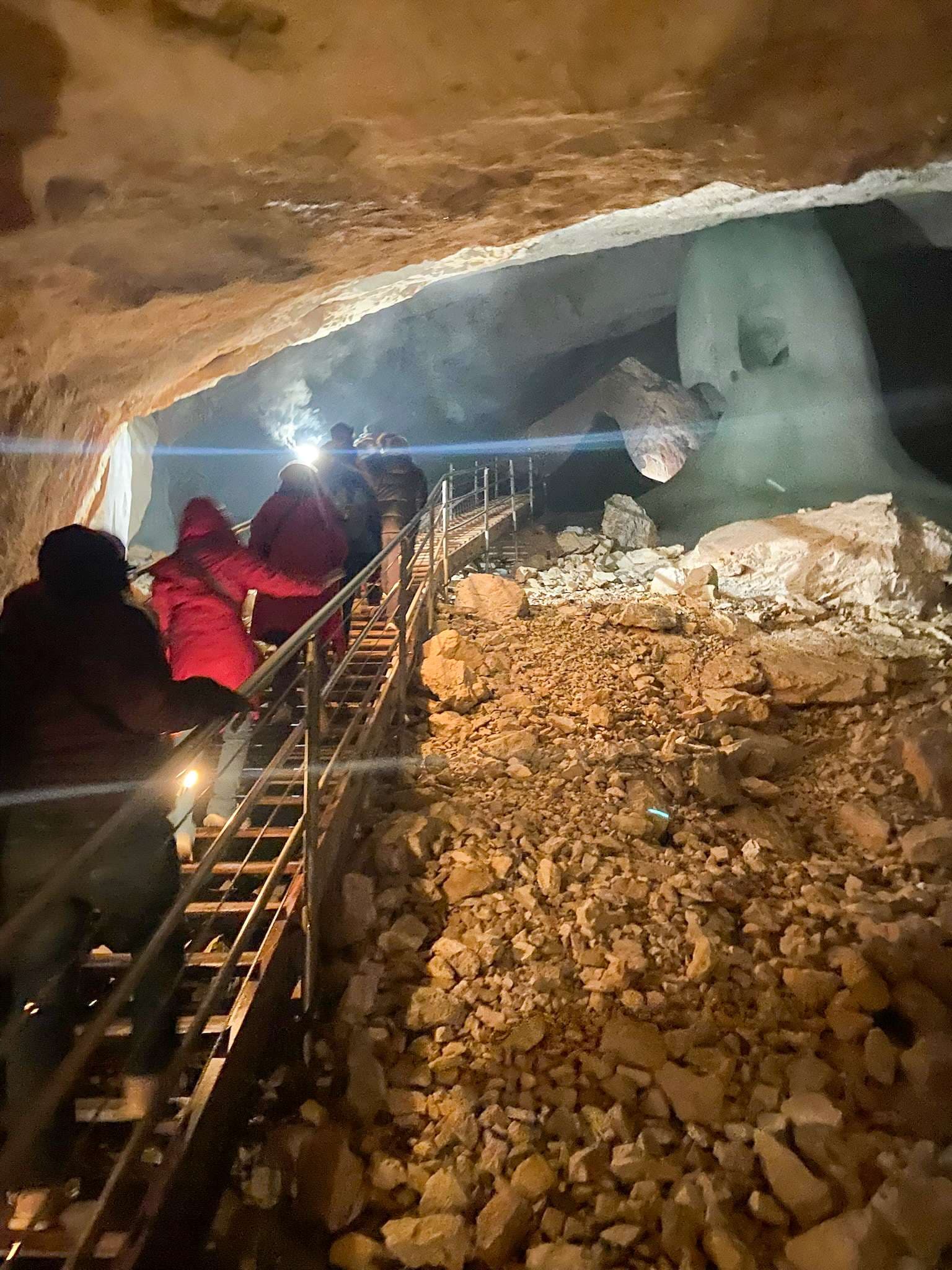 People are looking at a large ice bear in a cave.