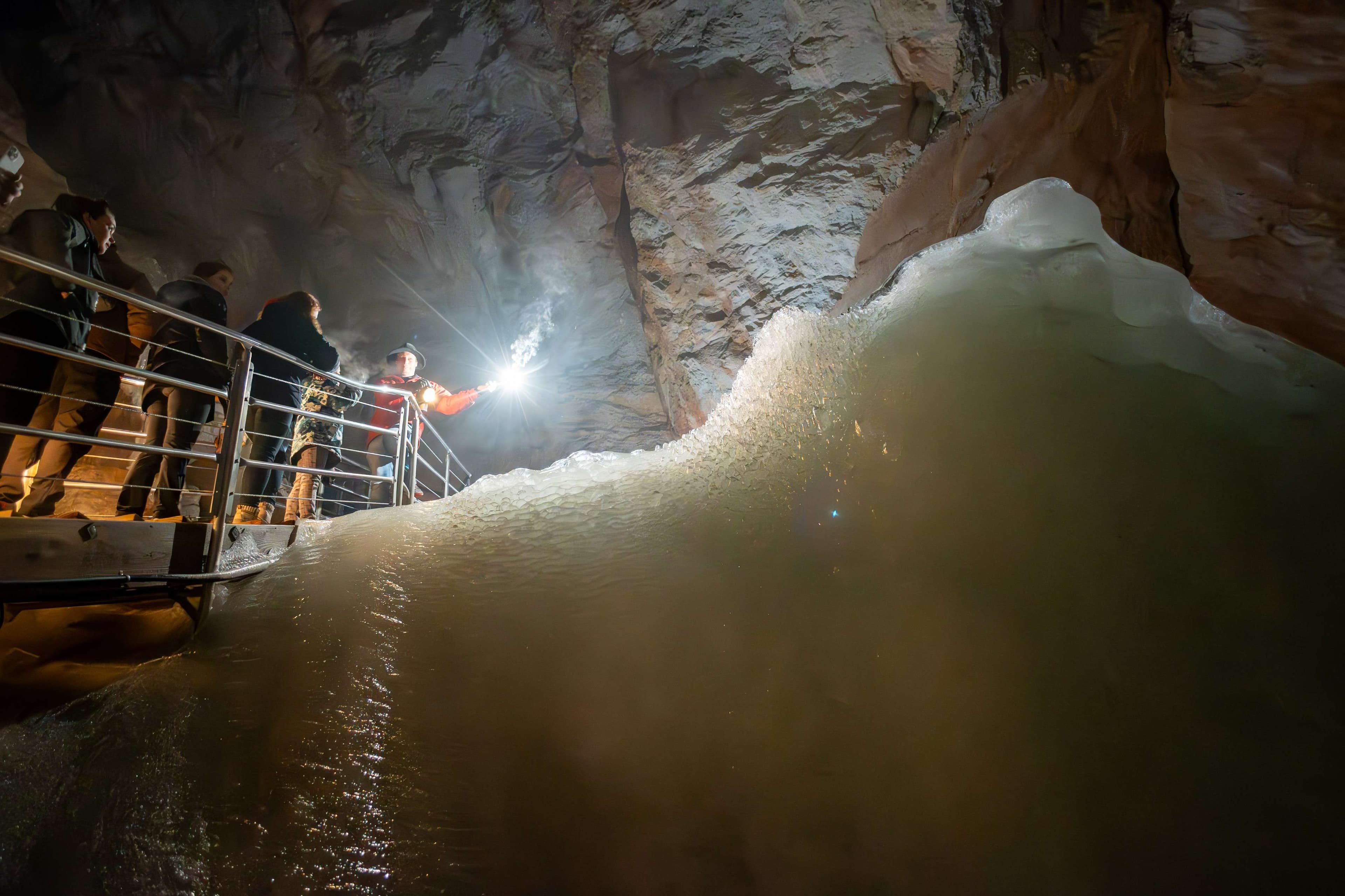 People standing on a boat in a cave with a light on.
