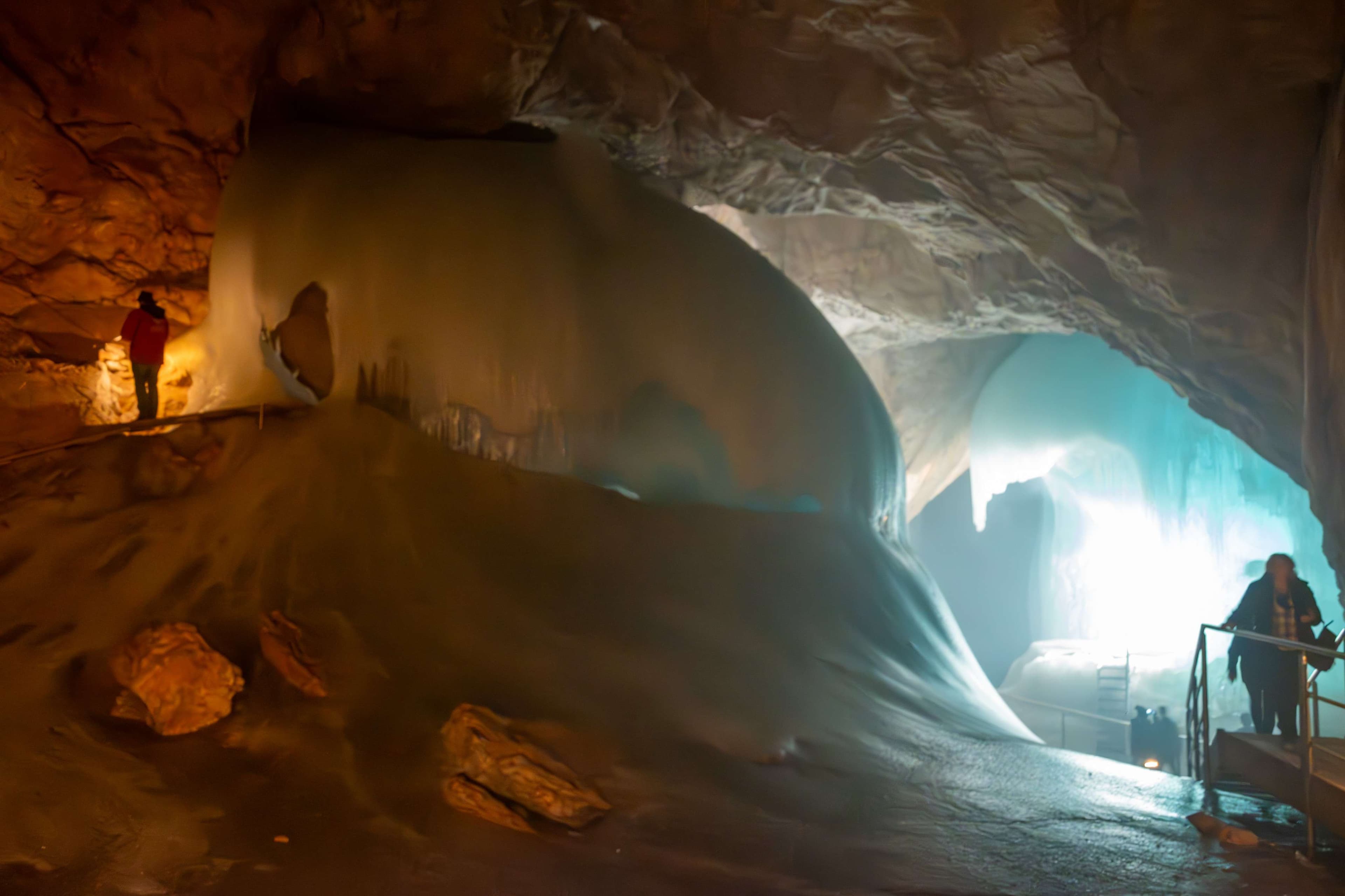 People are standing in a cave with a light at the end.