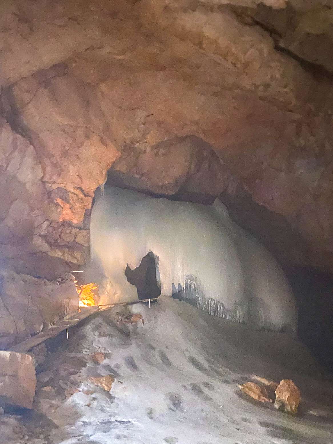 There is a man standing in a cave with a fire.