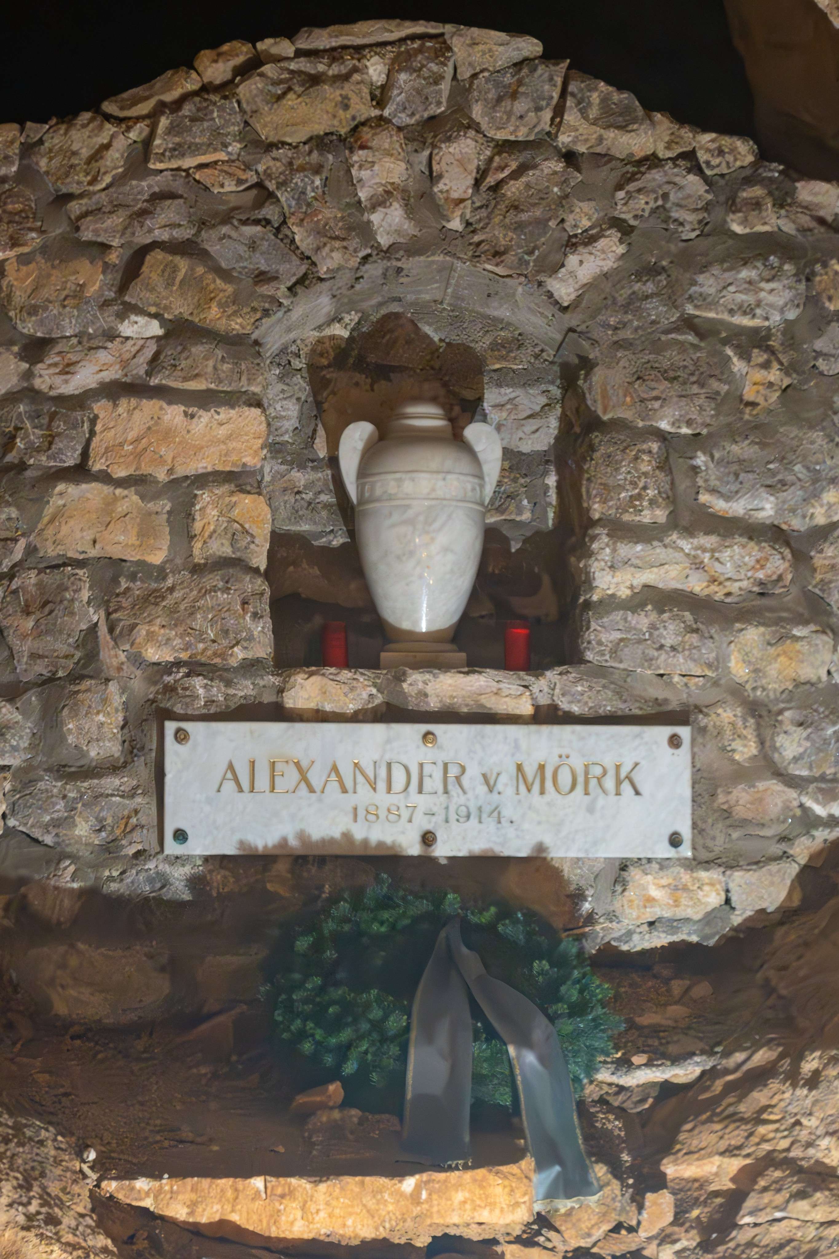 There is a stone wall with a sign and a vase on it.