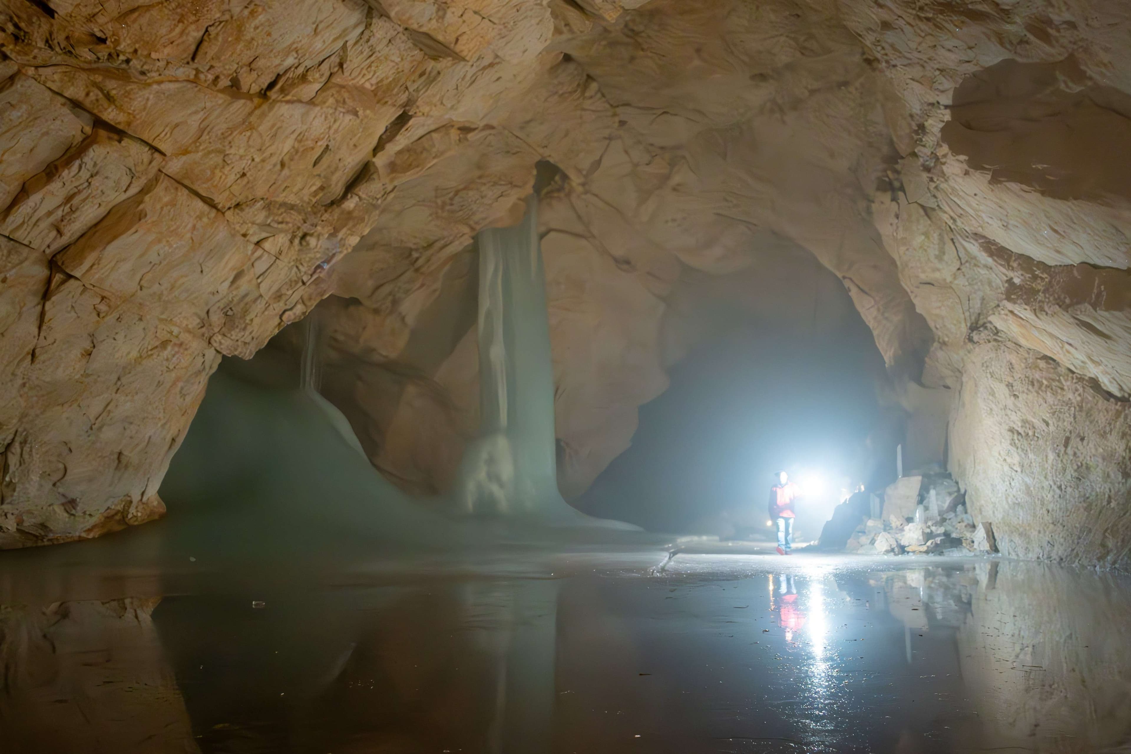 There is a man standing in a cave with a flashlight.