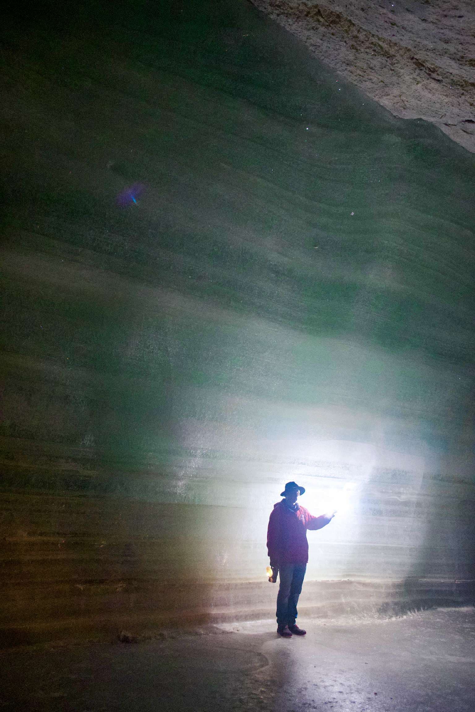 There is a man standing in a cave with a flashlight.