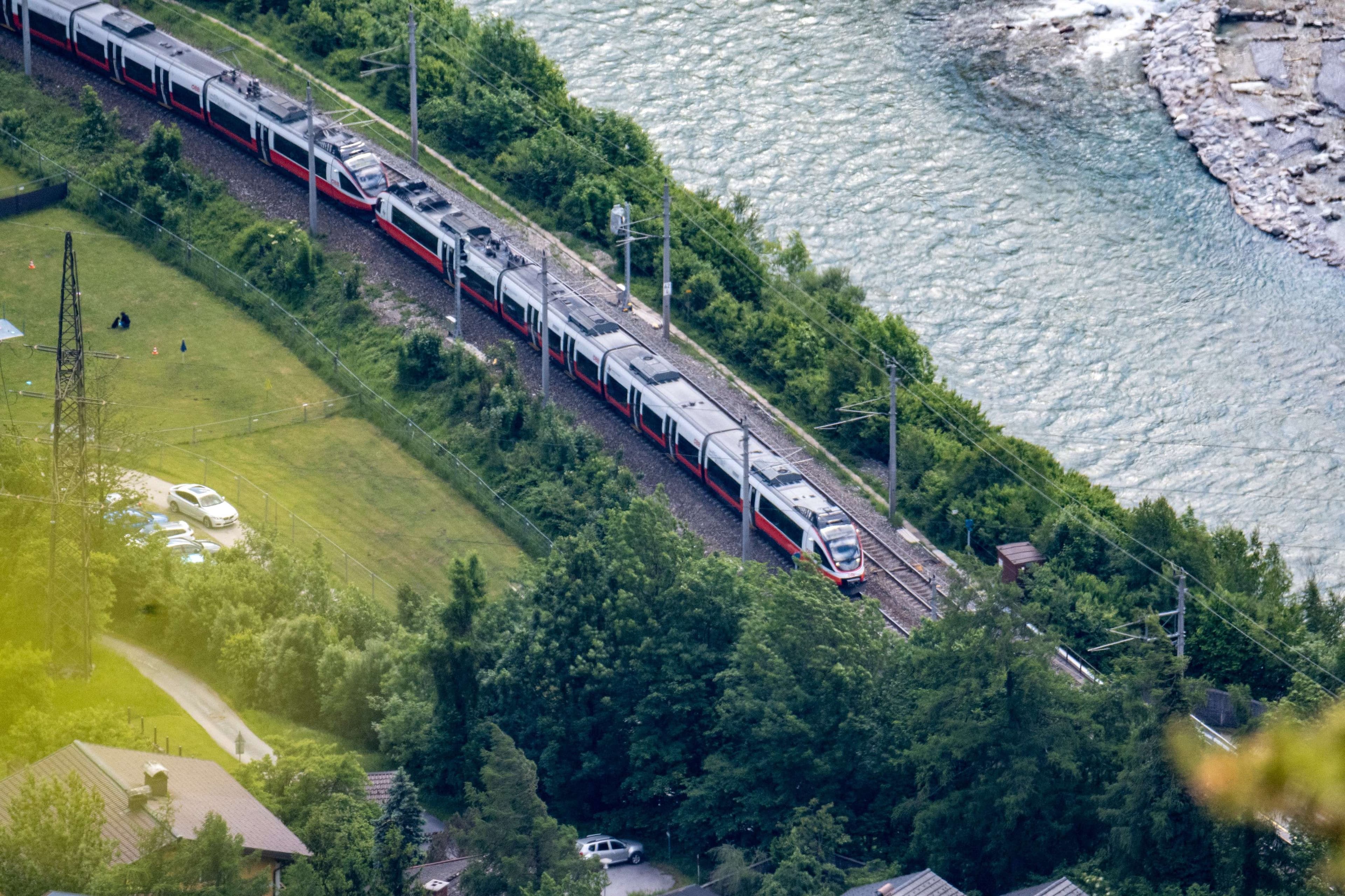 Arafed train on tracks next to a river and a road.