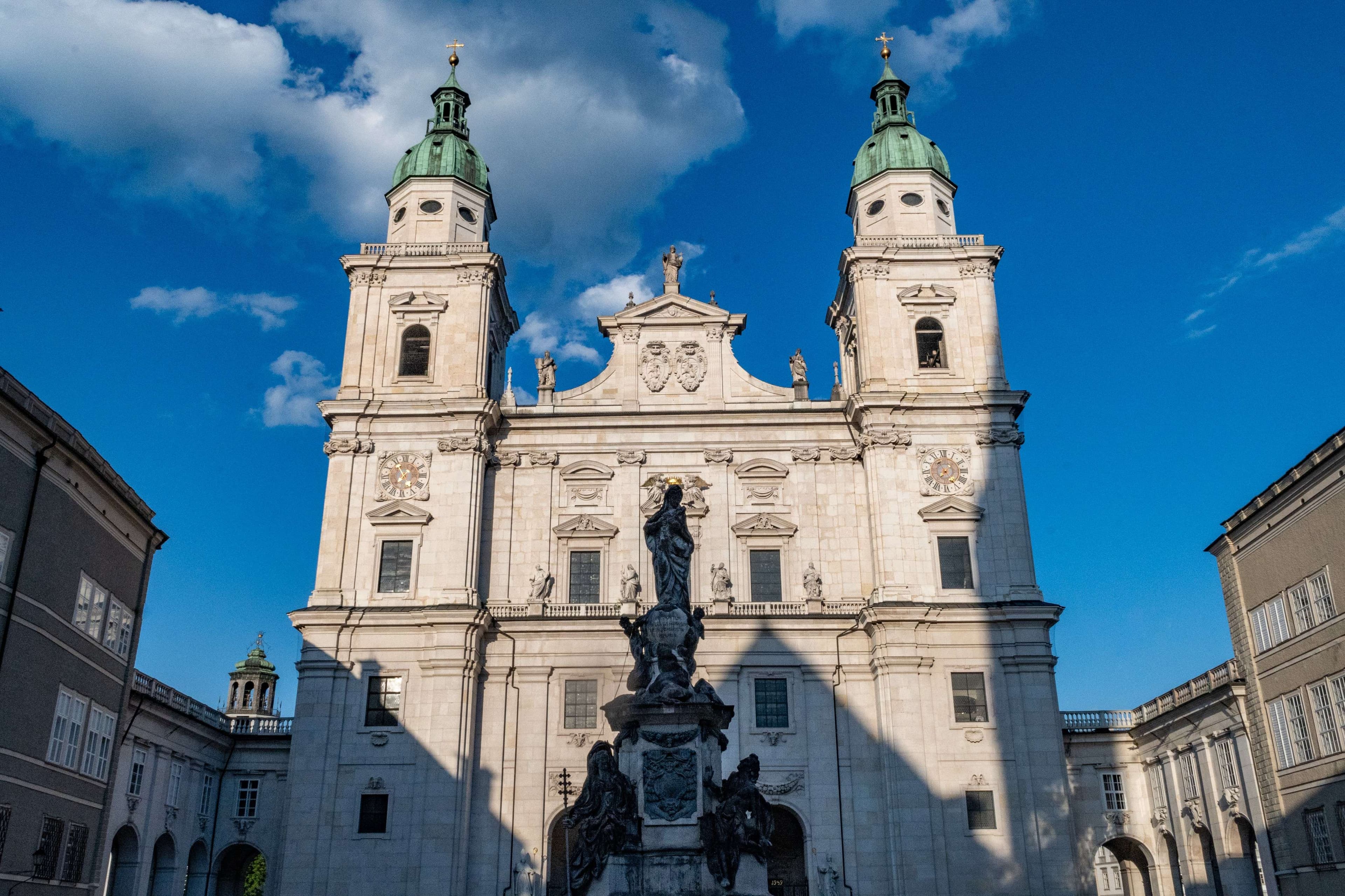 There is a statue in front of a large building with a clock on it.