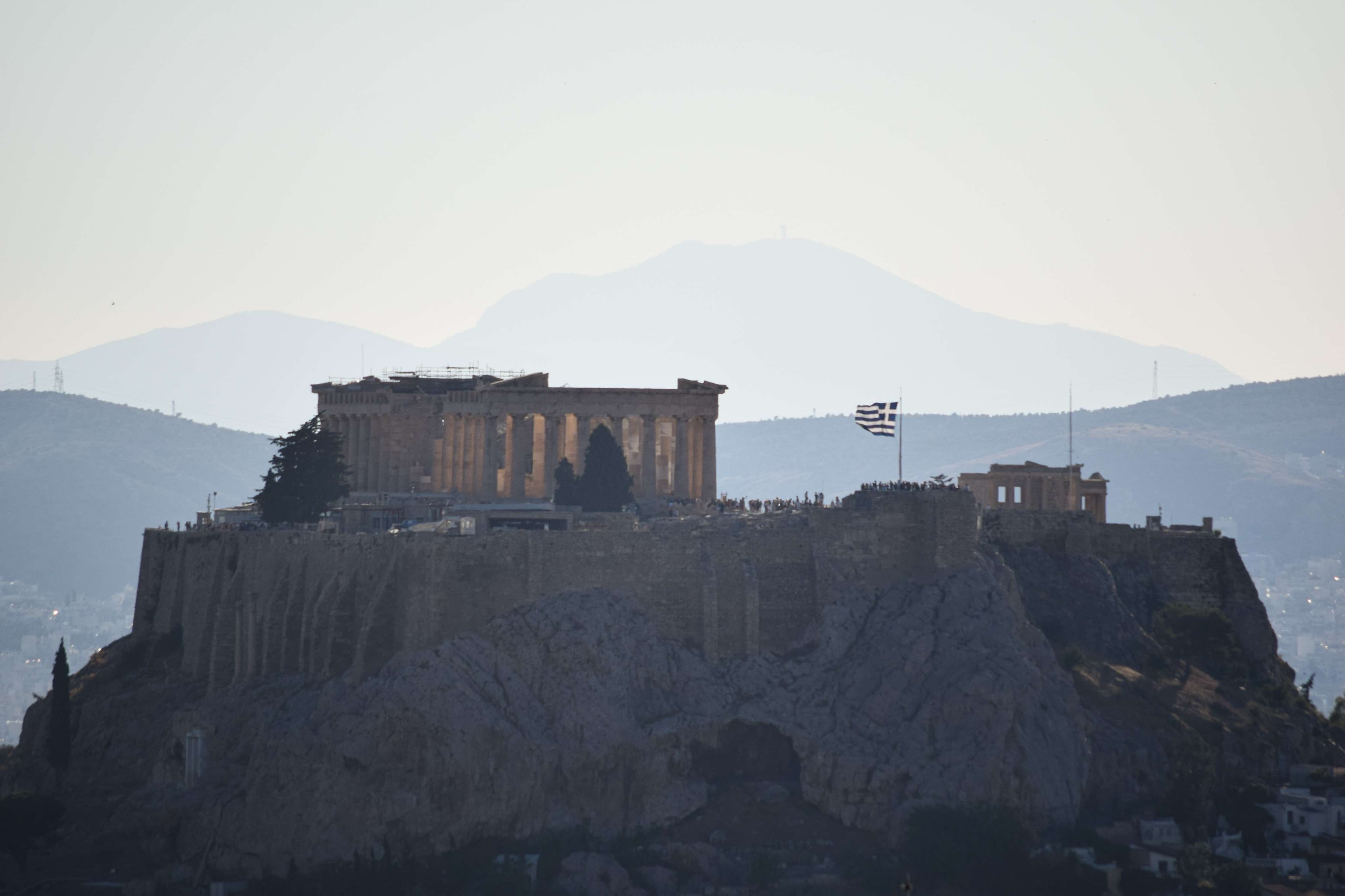 There is a large building on top of a hill with a flag flying.