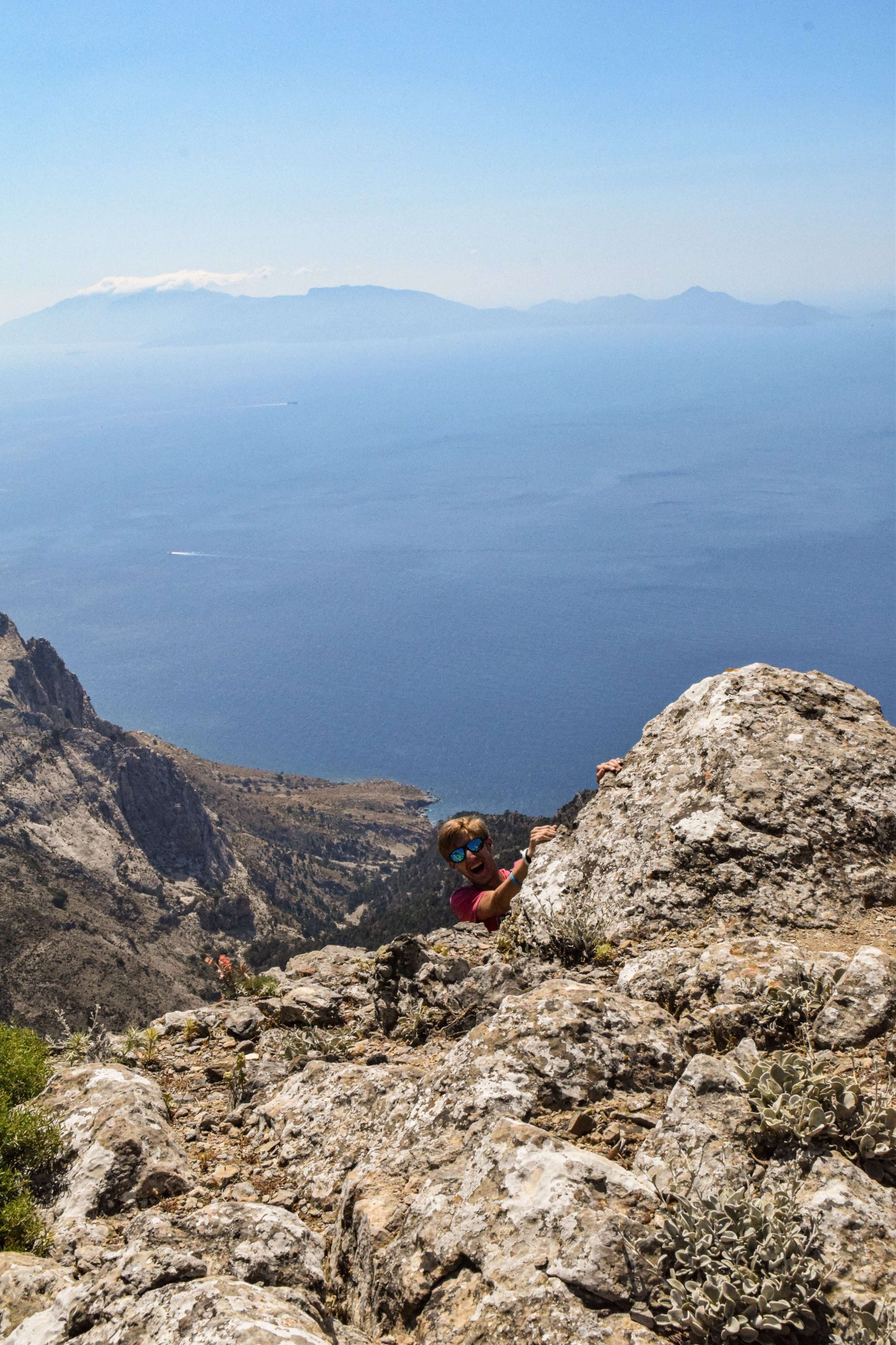 There is a person sitting on a rock on a mountain.