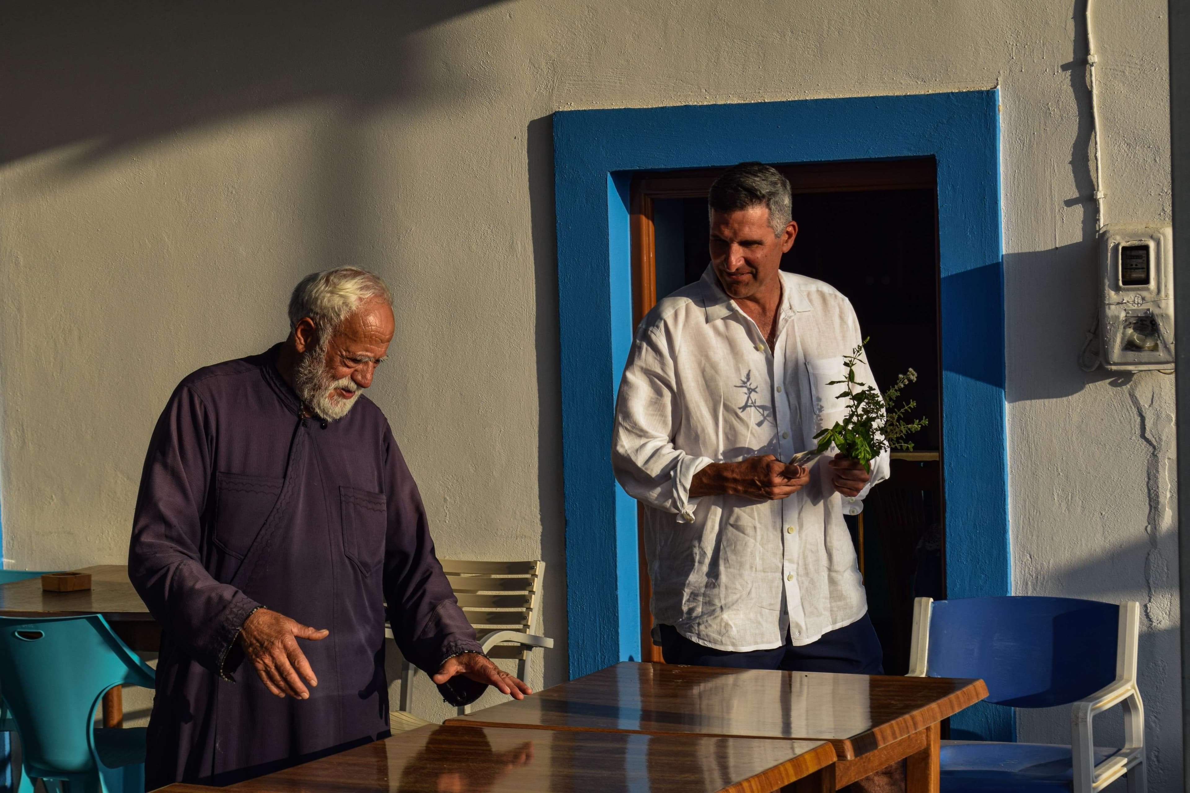 They are standing outside of a building with a table and chairs.