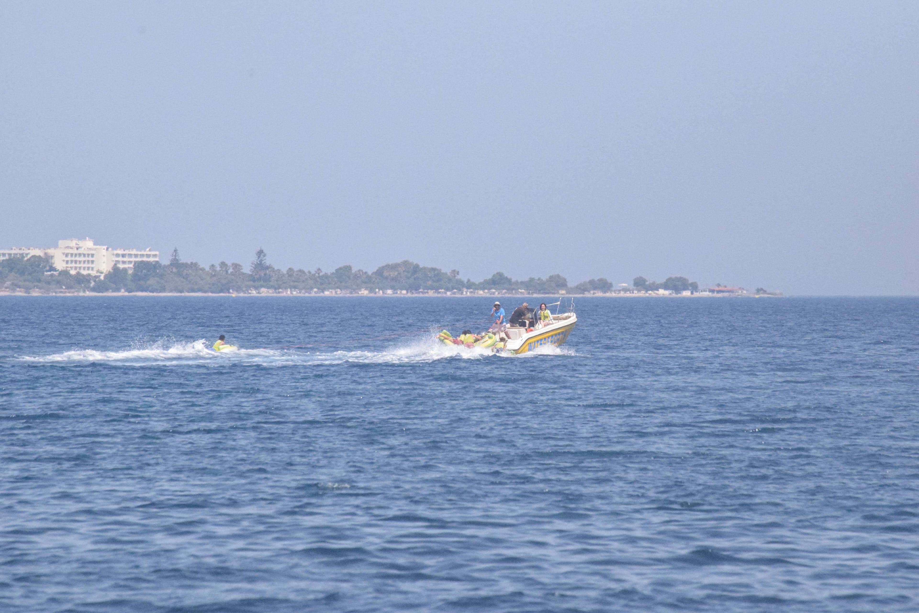 There is a boat that is going through the water with people on it.