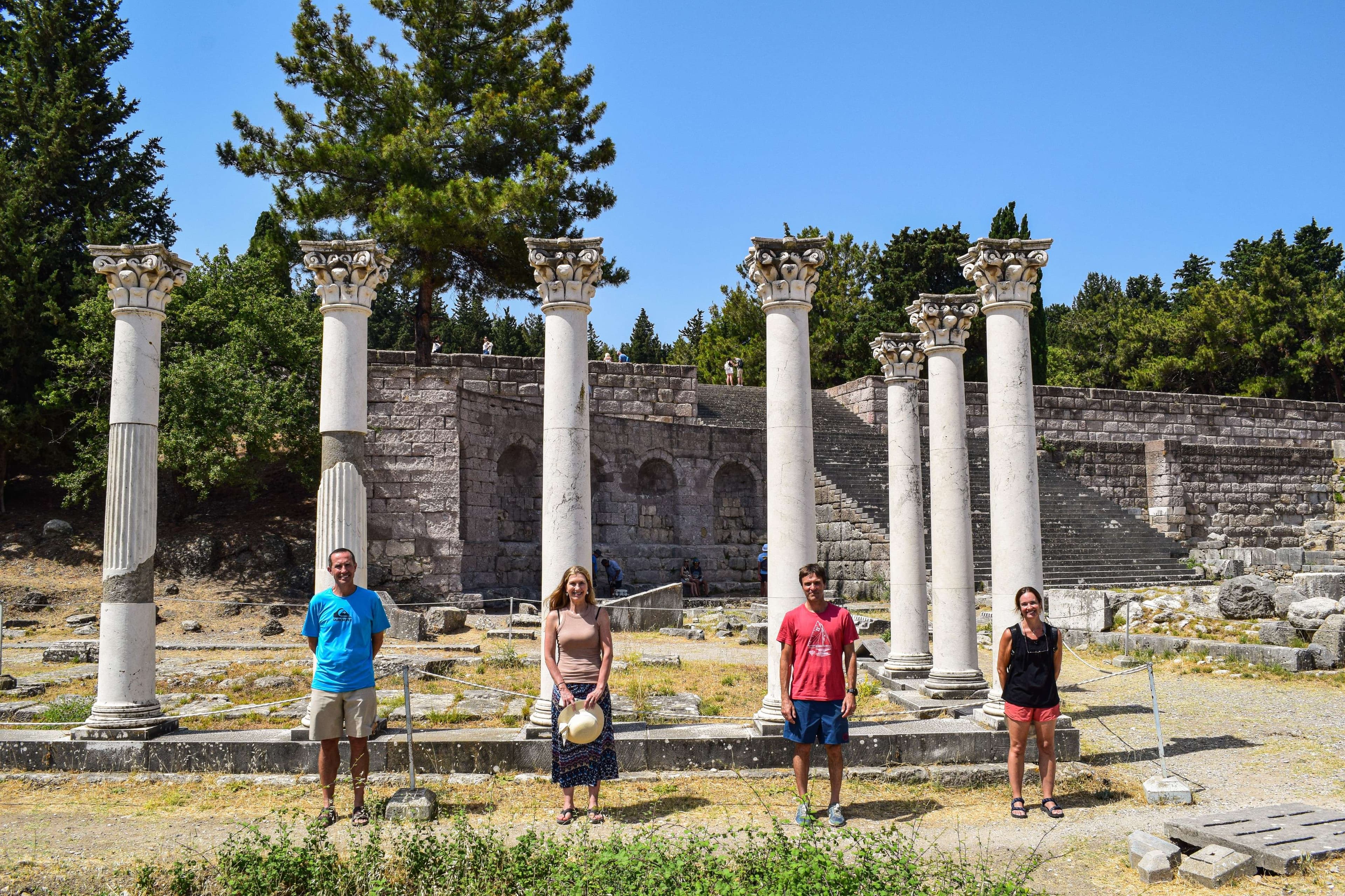 Several people standing in front of a row of columns in a park.