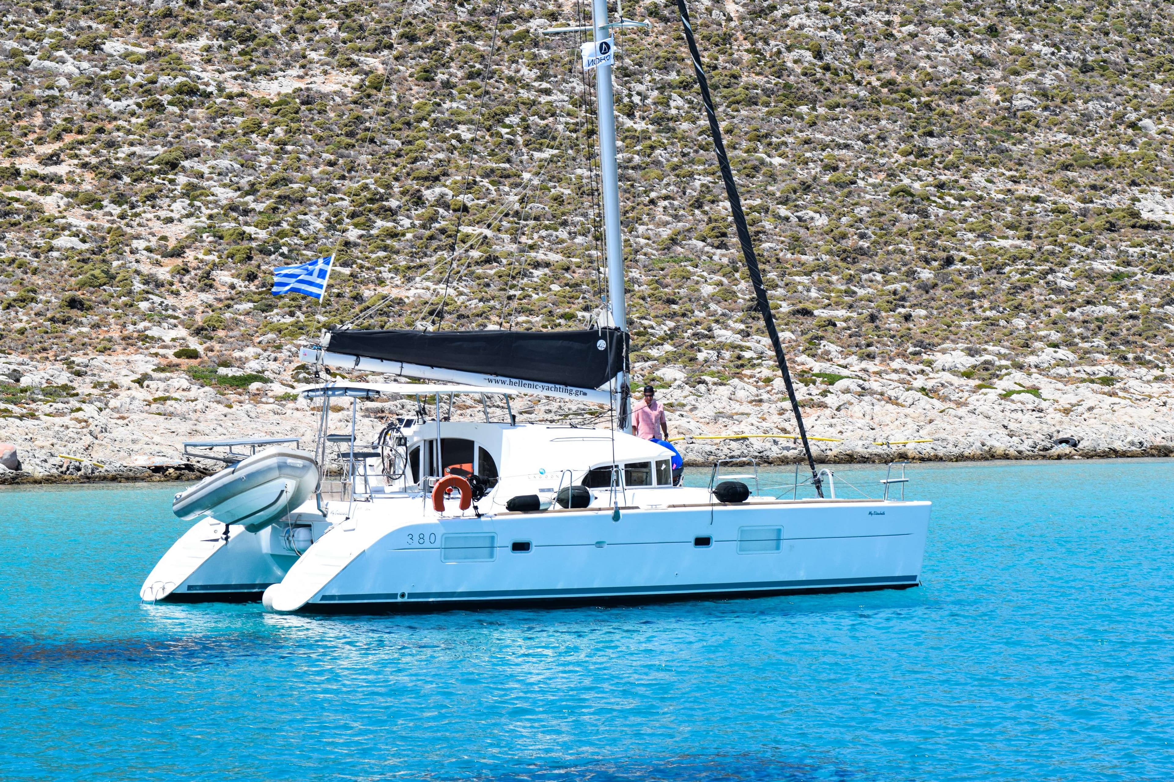 There is a white boat with a black sail on the water.