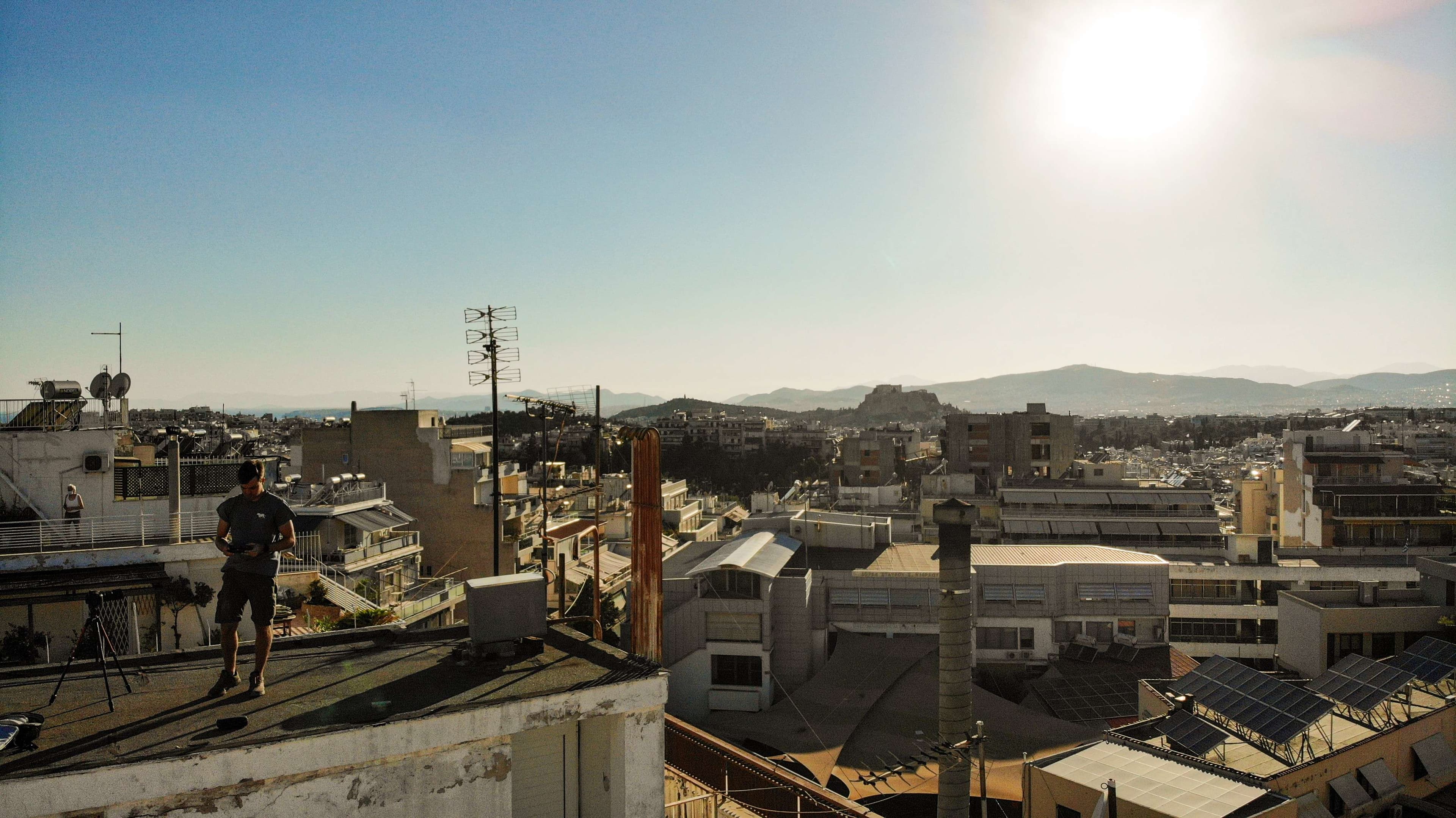 There is a man standing on a roof looking out over a city.