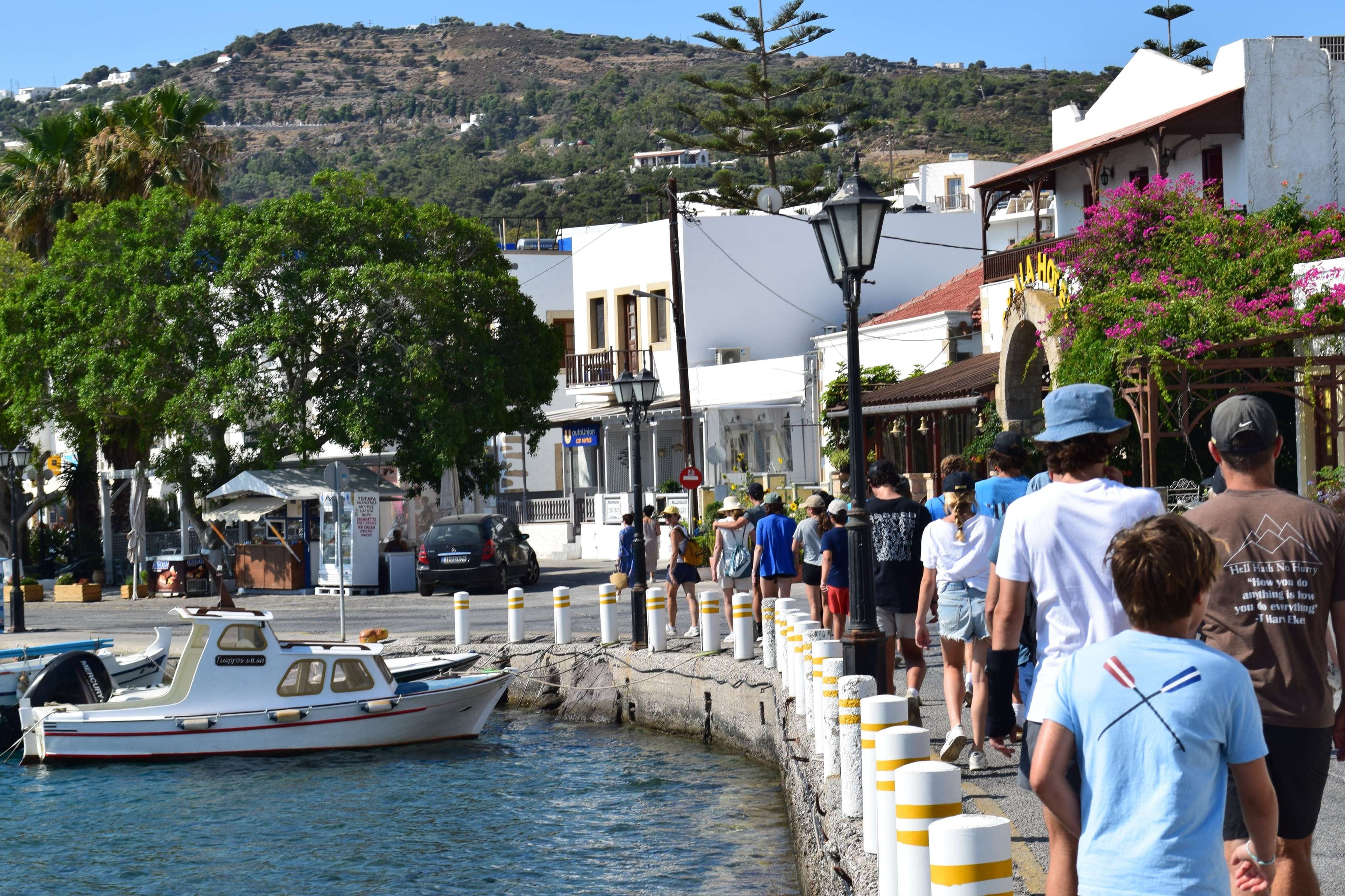 People walking along a pier with a boat in the water.