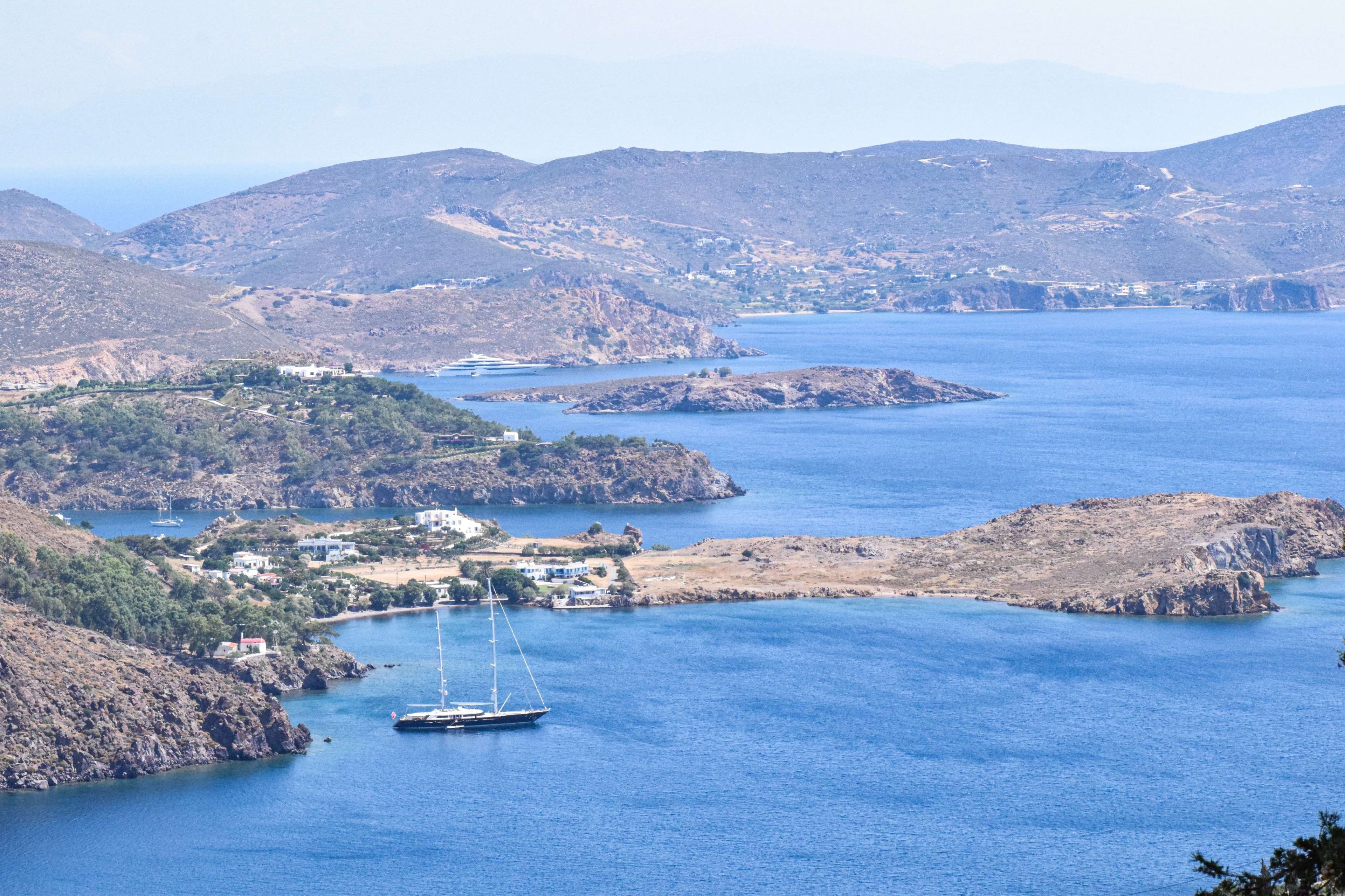 There is a boat that is floating in the water near the mountains.