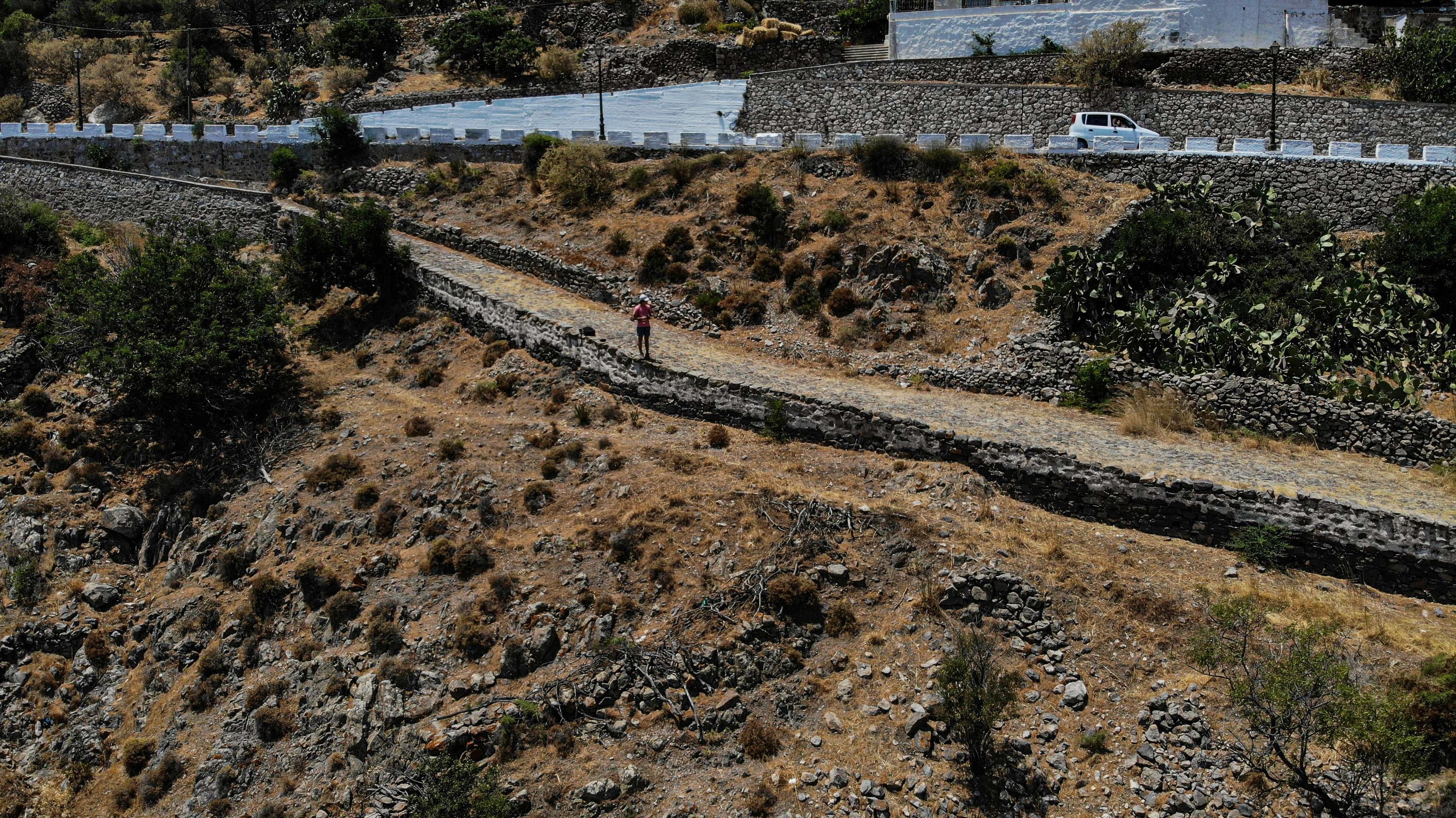 There is a man riding a bike down a dirt road.