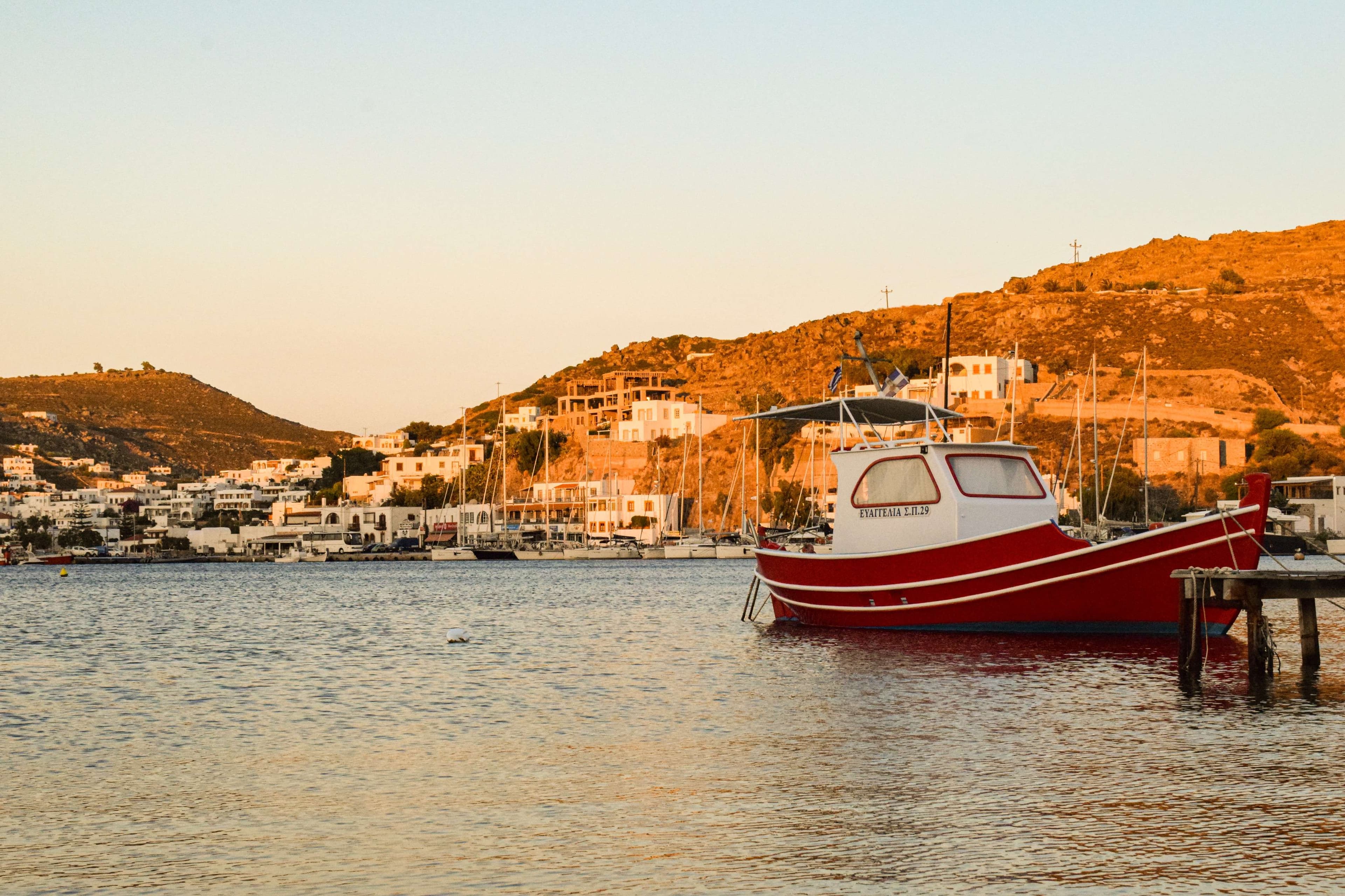There is a boat that is docked in the water near a dock.