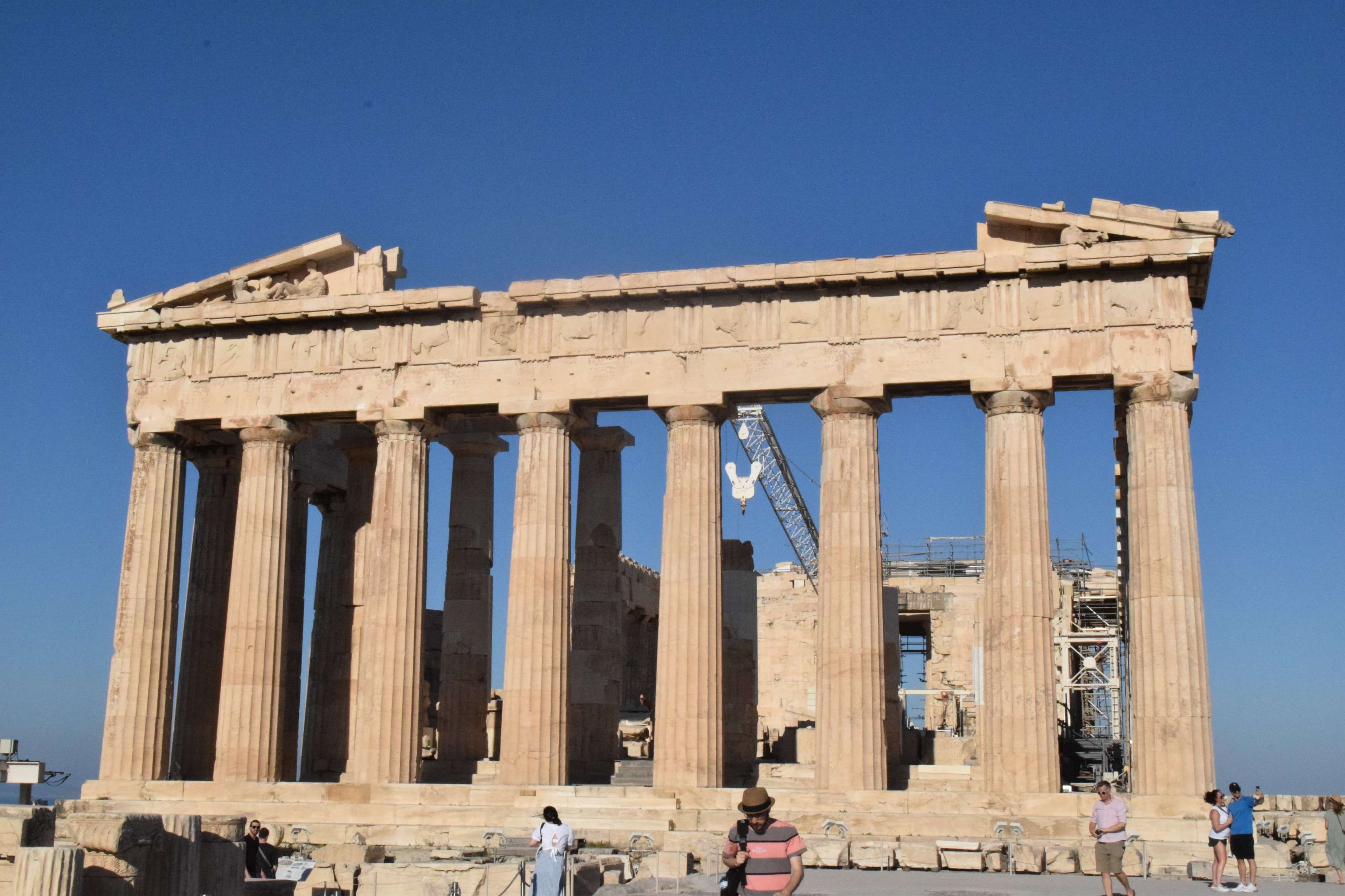 There are people standing in front of a large building with columns.